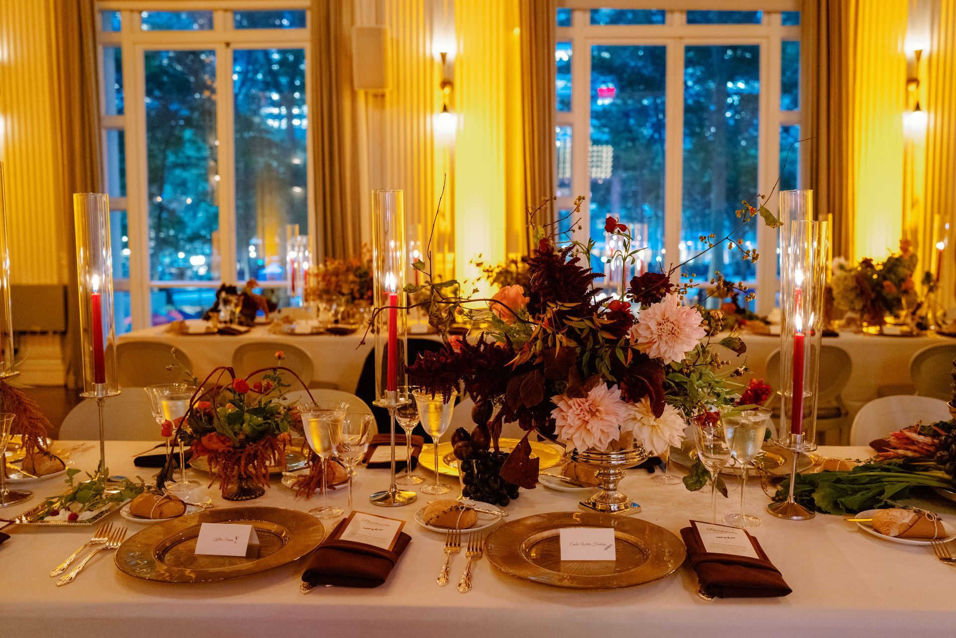 Elegant candlelit banquet table with flowers and place settings in a warmly lit room