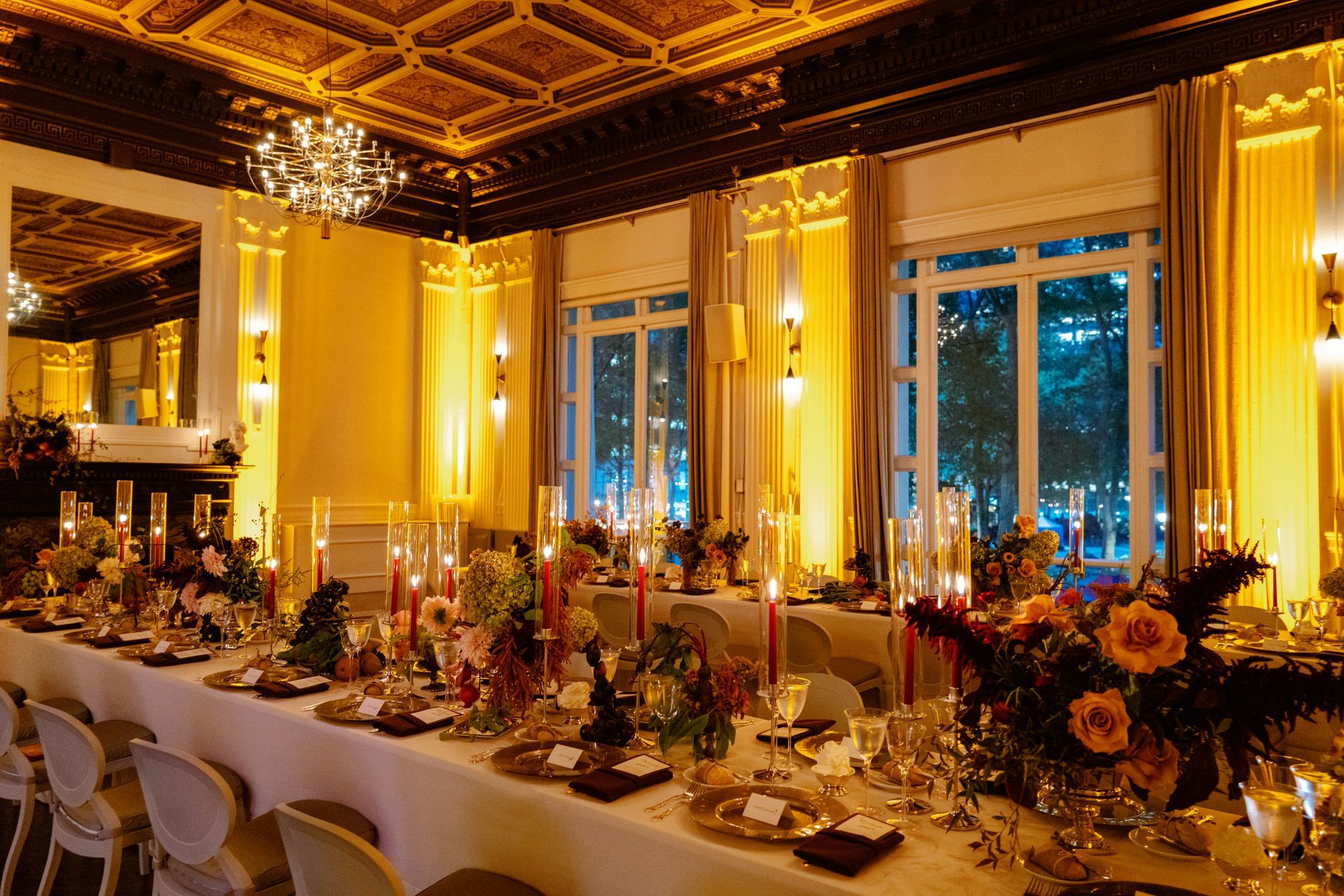 Elegant banquet hall with candlelit tables, gold decor, and large windows at dusk