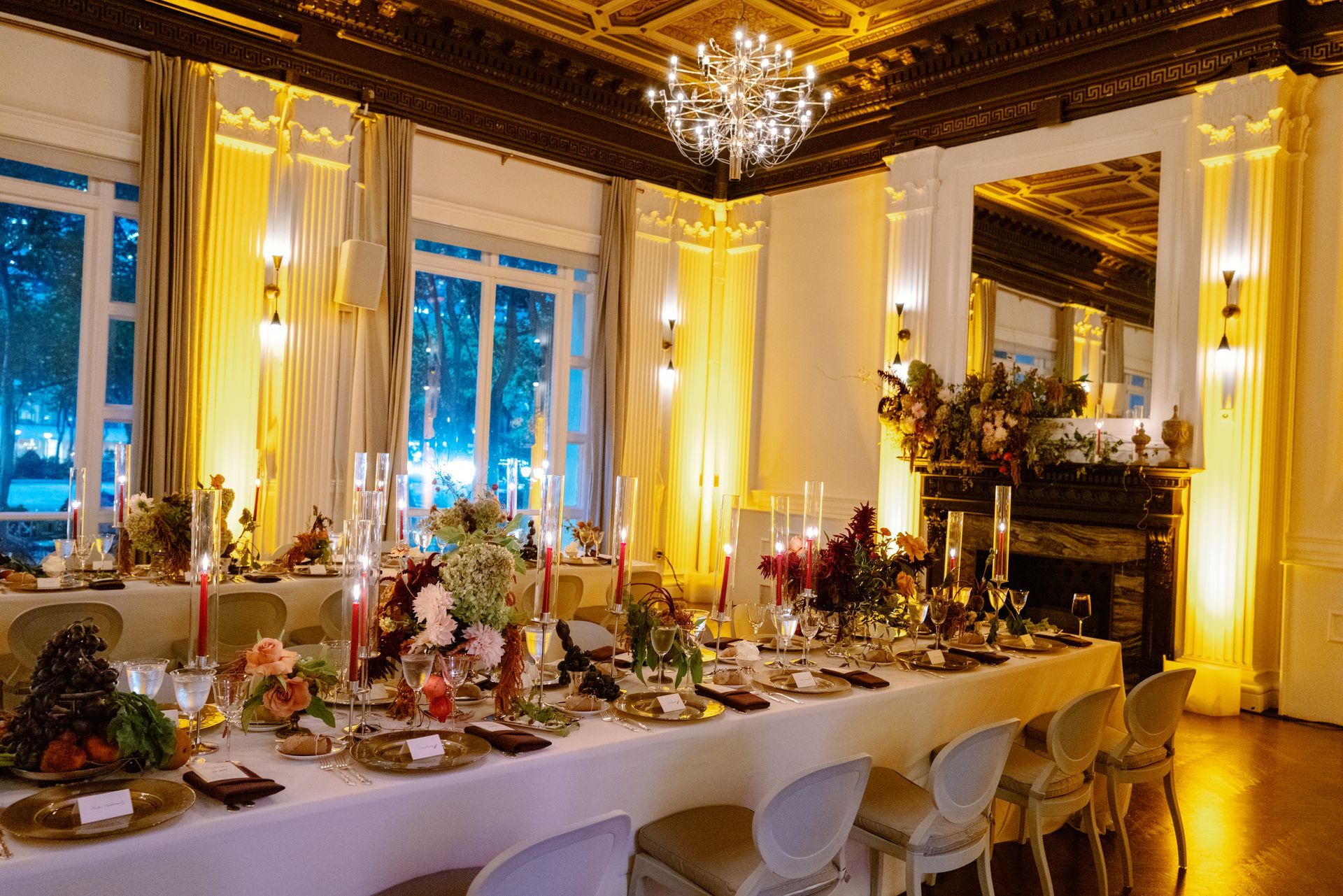 Elegant banquet table set in a gold-lit dining room with chandeliers and floral centerpieces
