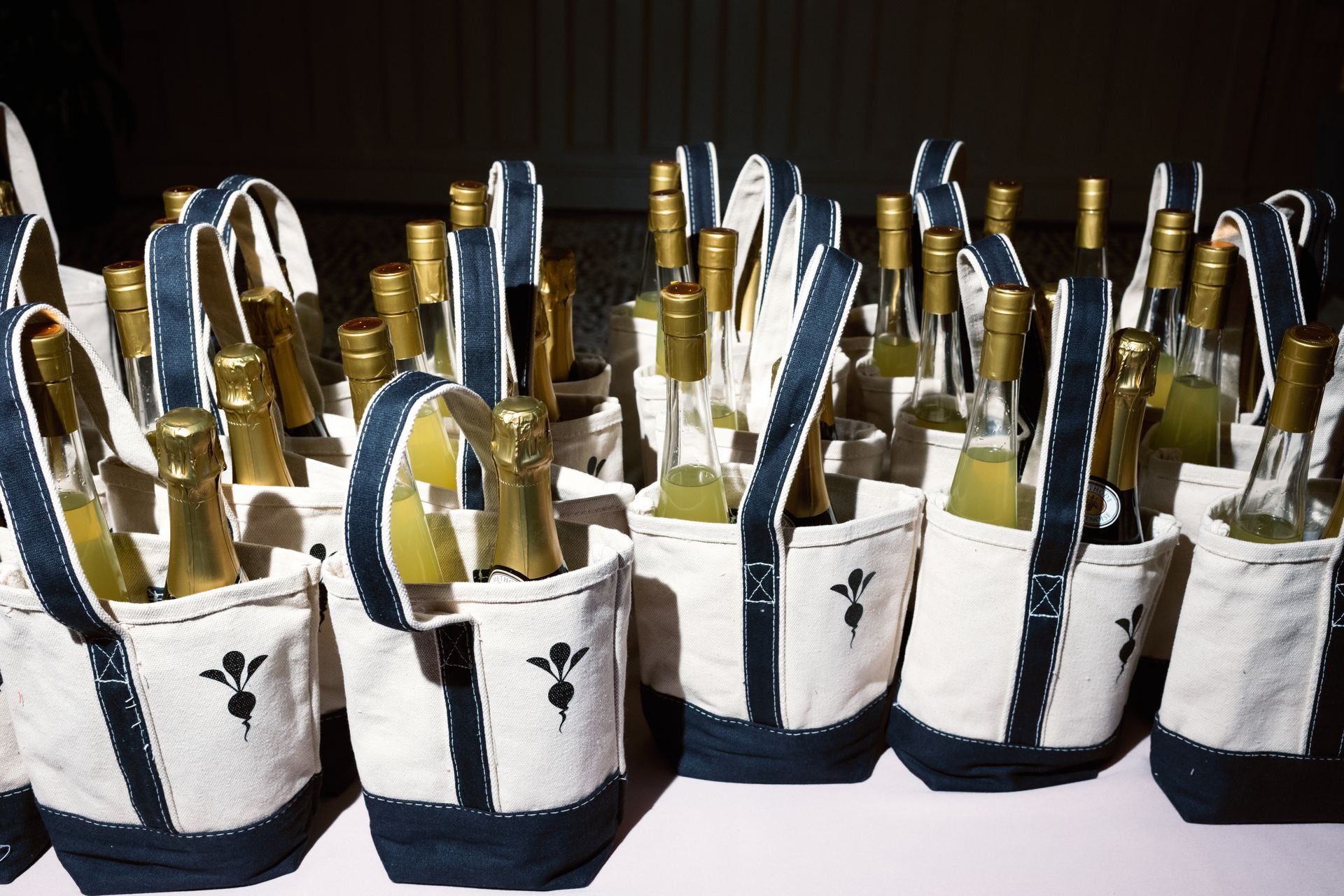 Rows of champagne bottles in white sleeves and black ribbon, arranged on a table for an event