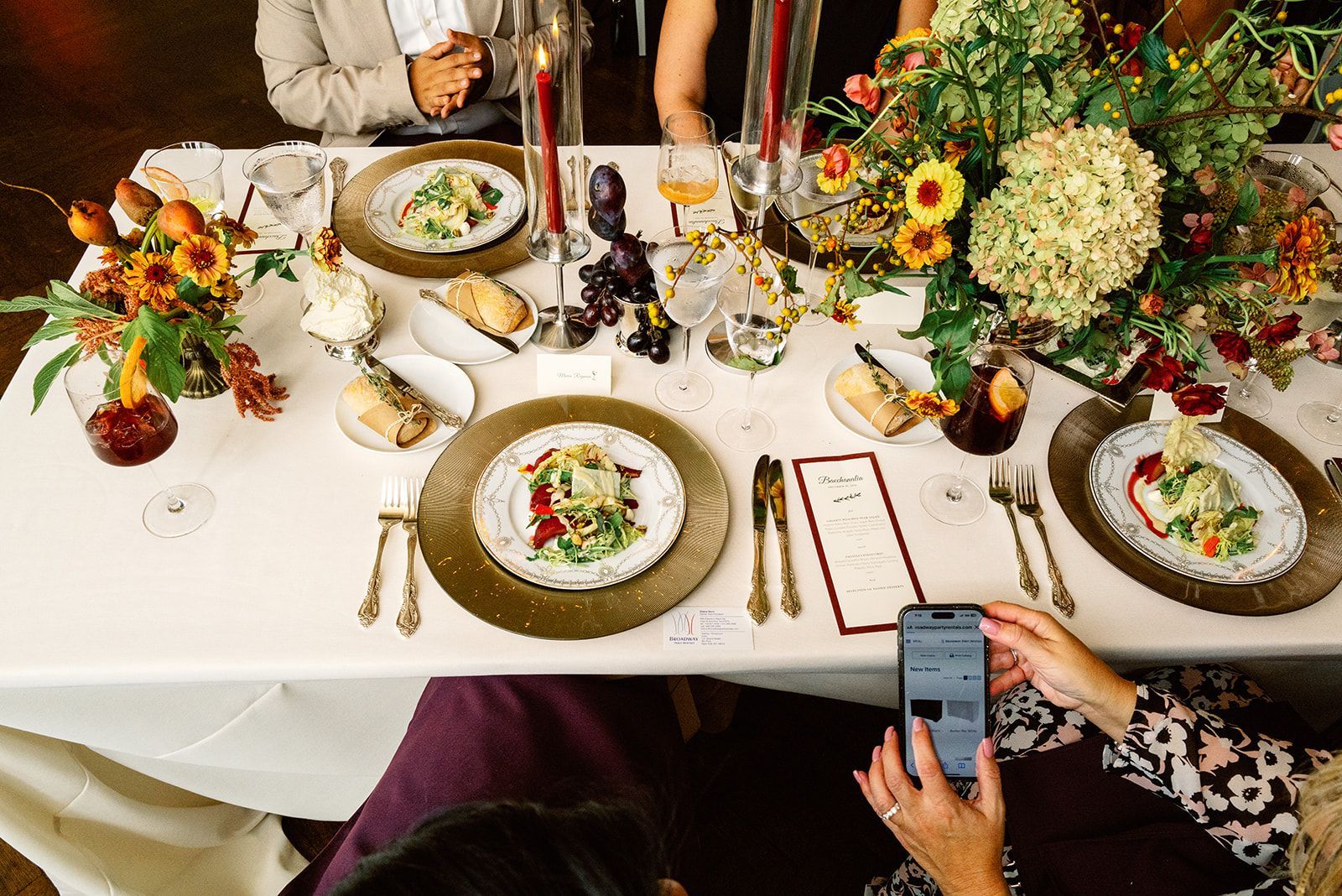 A woman is taking a picture of a table set for a wedding reception.