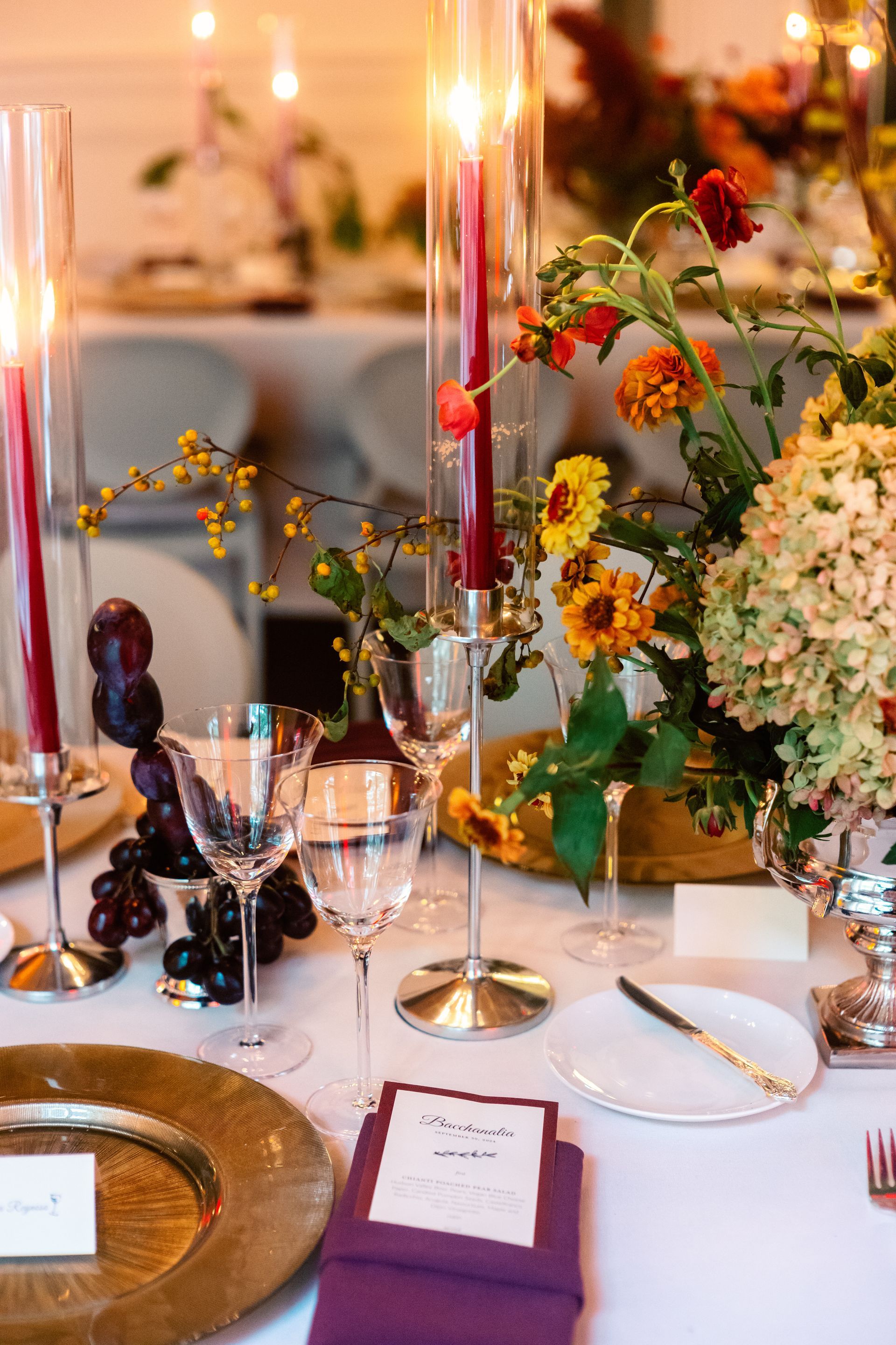 Elegant banquet table with candles, flowers, glassware, and gold accents in warm lighting