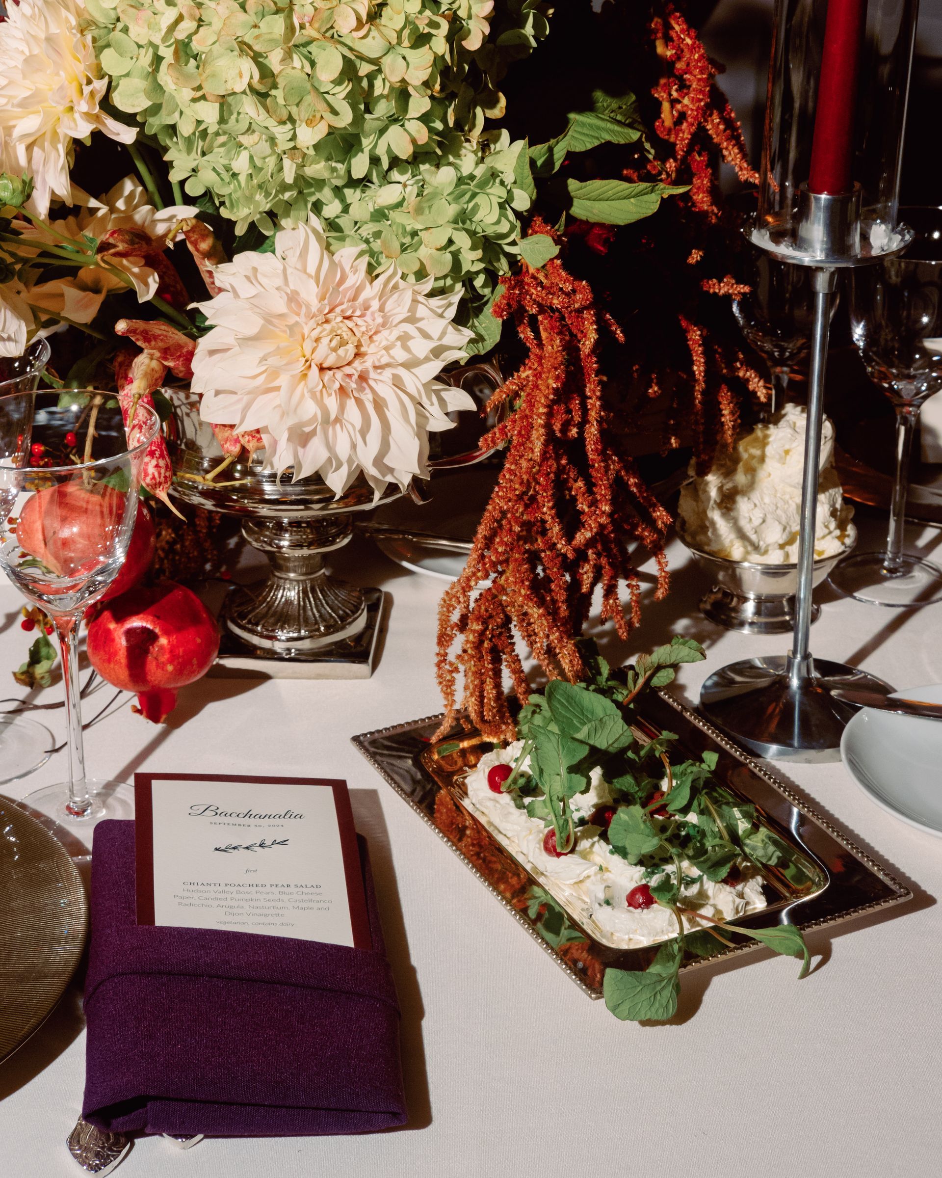Autumn floral arrangement with candles, red berries, a purple napkin, and a decorated tray on a white table