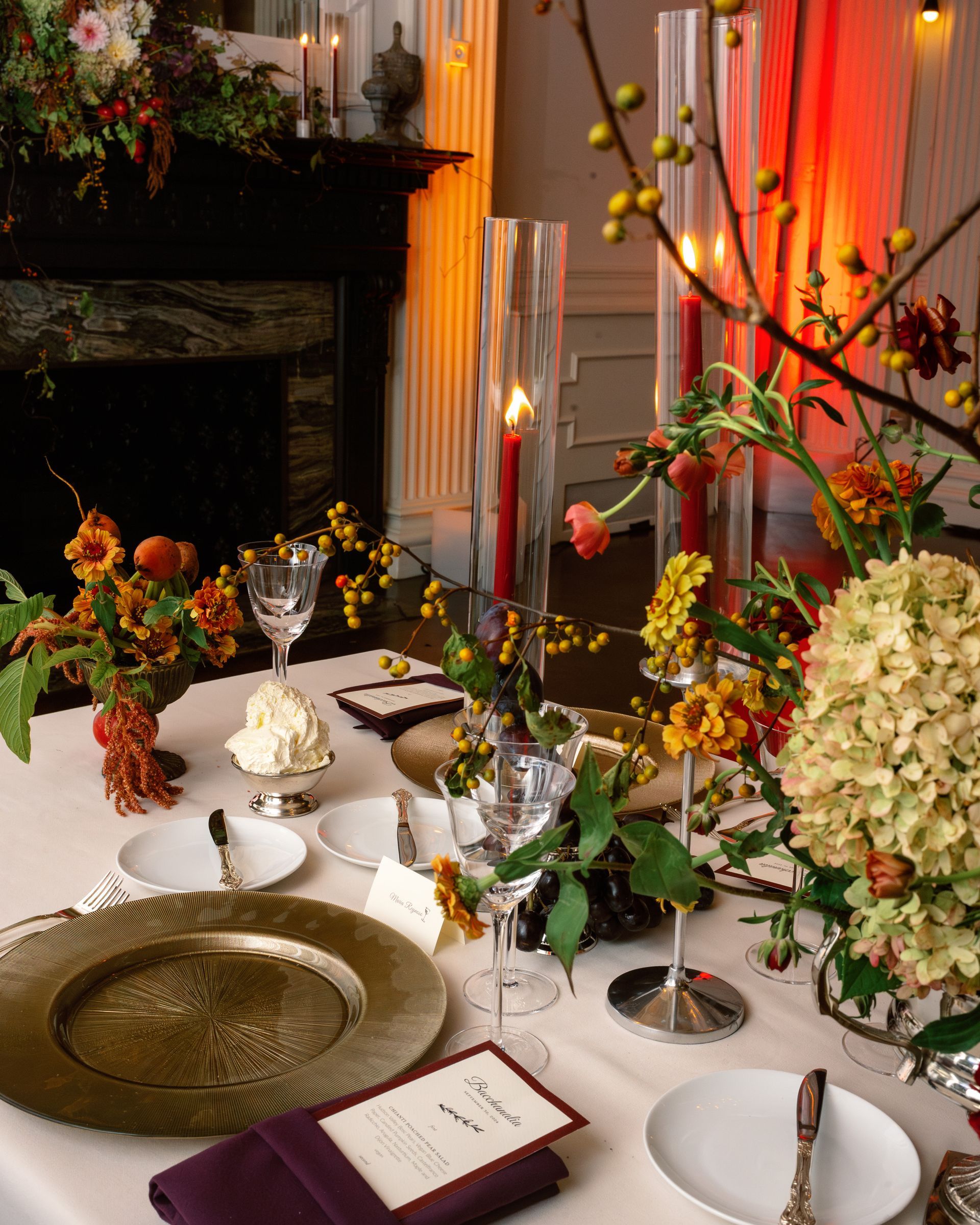 Elegant floral table setting with gold and white decor, candlelight, and tall glass vases at an event venue