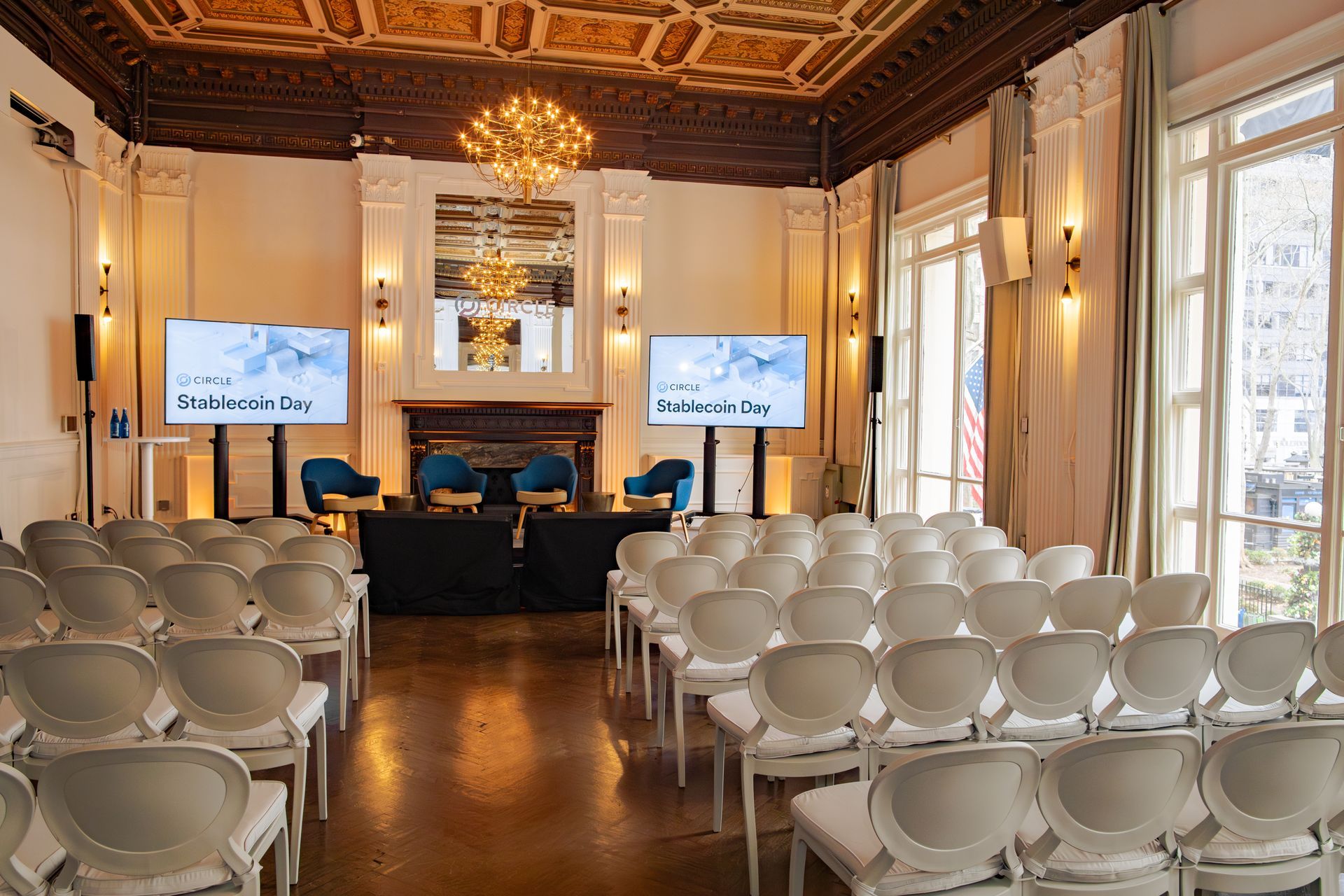 Elegant conference room with rows of white chairs facing a stage and two presentation screens