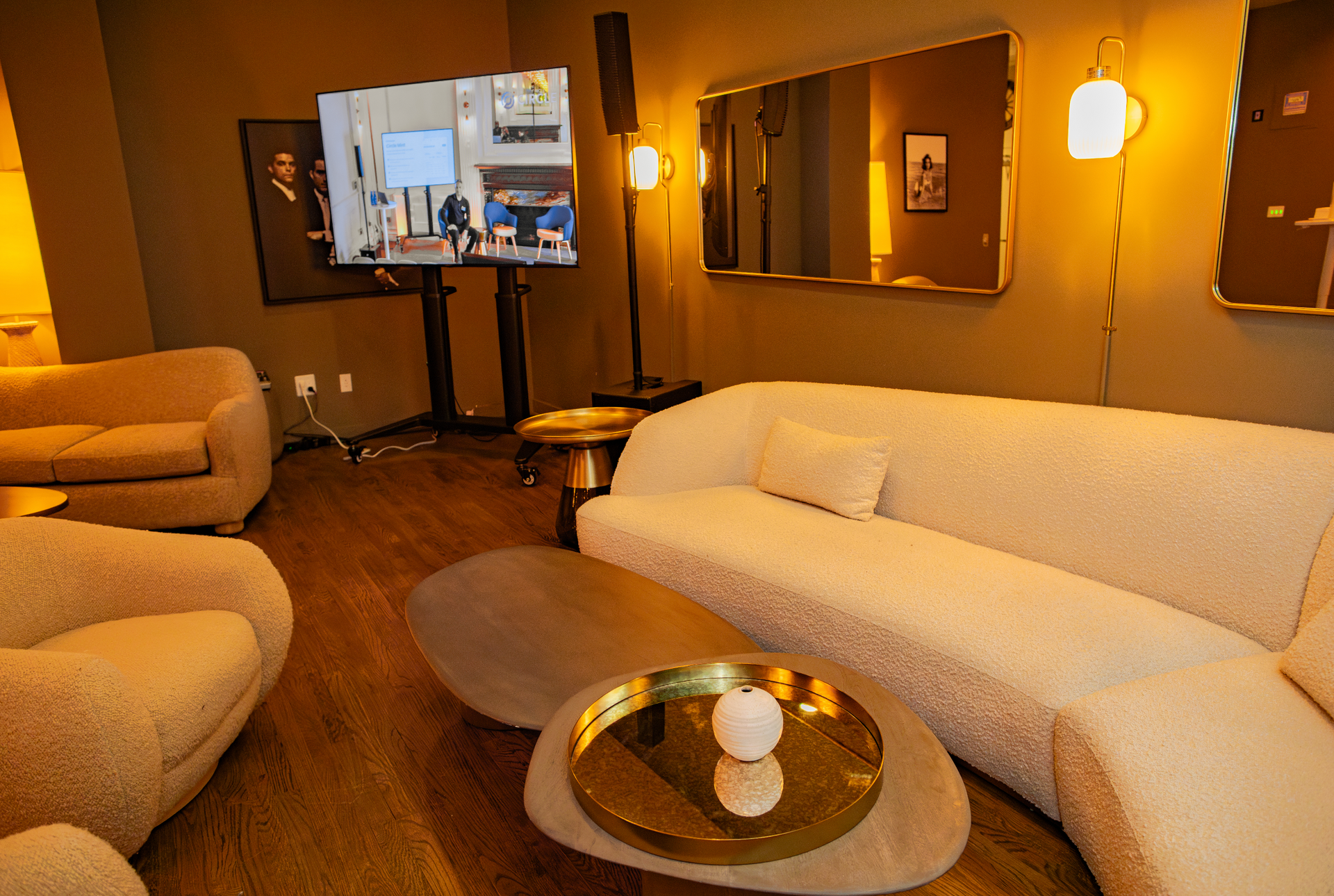 Modern living room with beige sofas, warm lighting, and a TV on a stand.