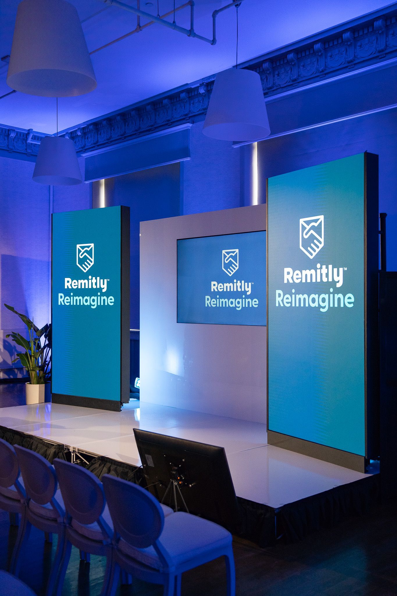 Blue-lit stage with three “Bentley” branded screens at a corporate event