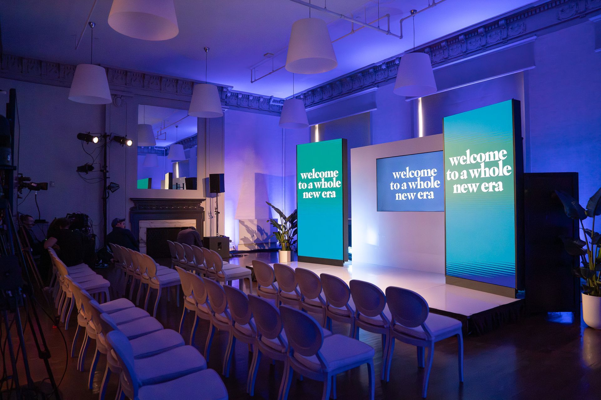 Empty conference room with rows of chairs and blue-lit presentation screens at the front