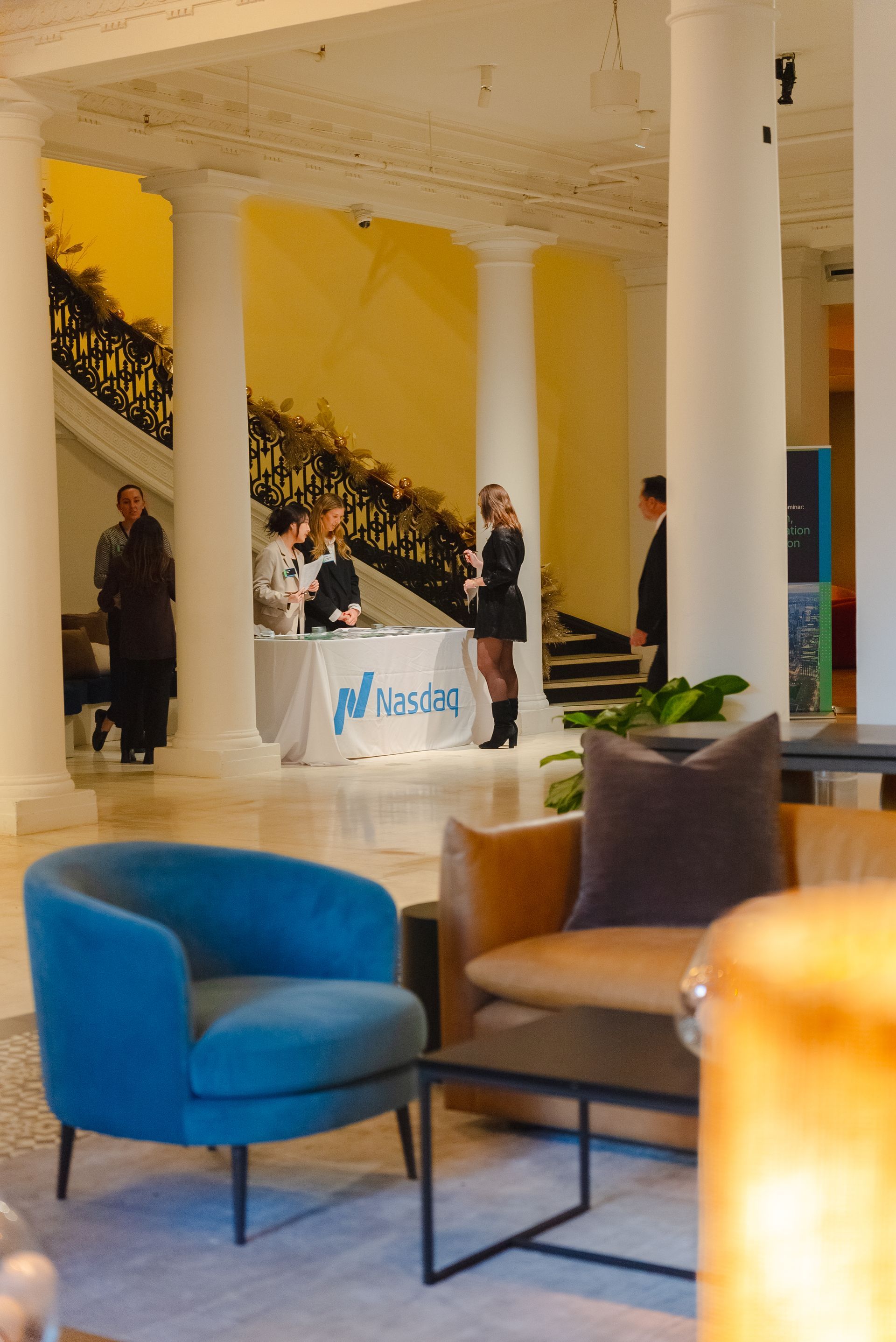 Elegant lobby with blue chairs, marble columns, and people gathered at a reception desk