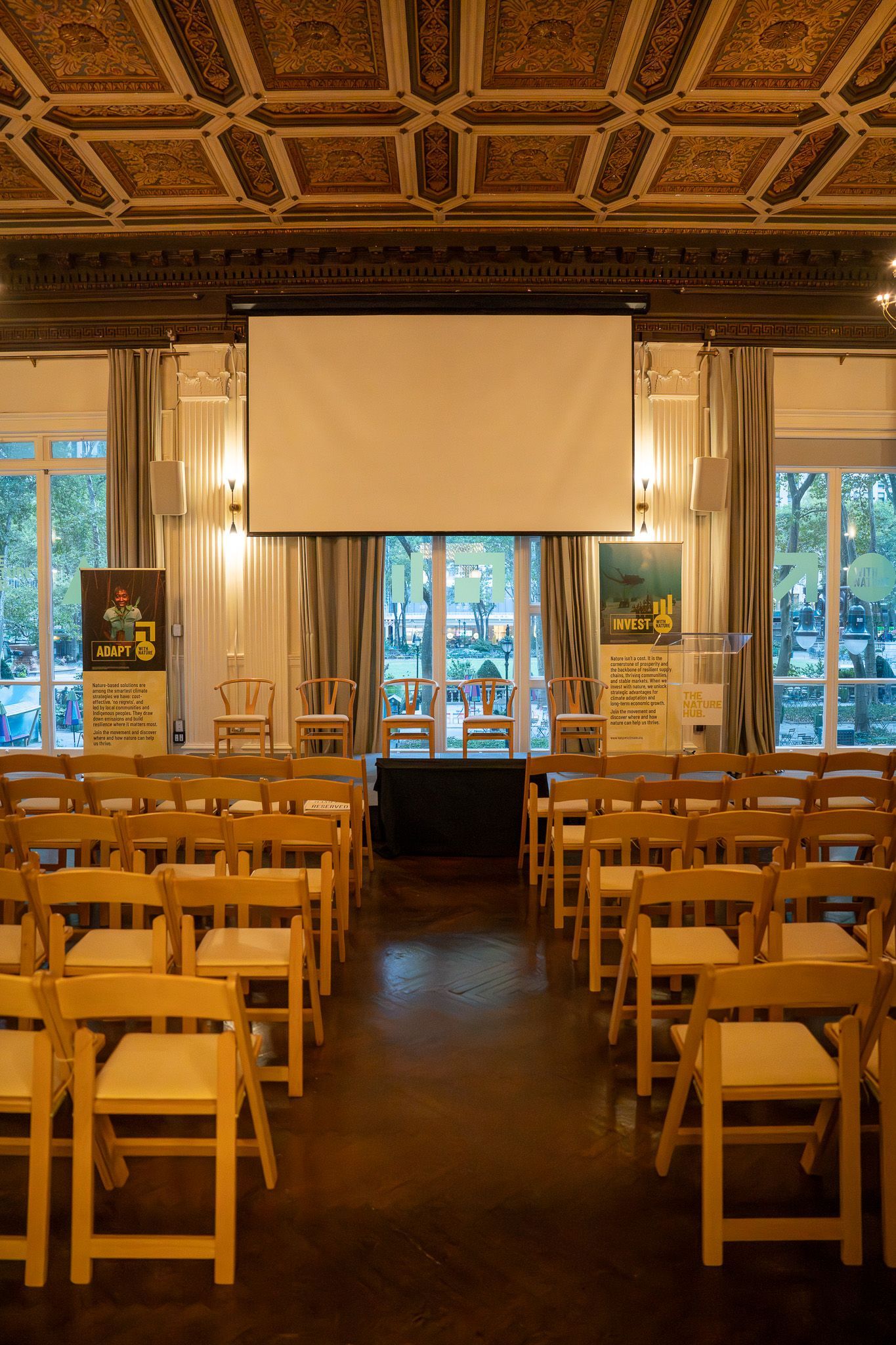 Empty conference room with rows of wooden chairs facing a projection screen