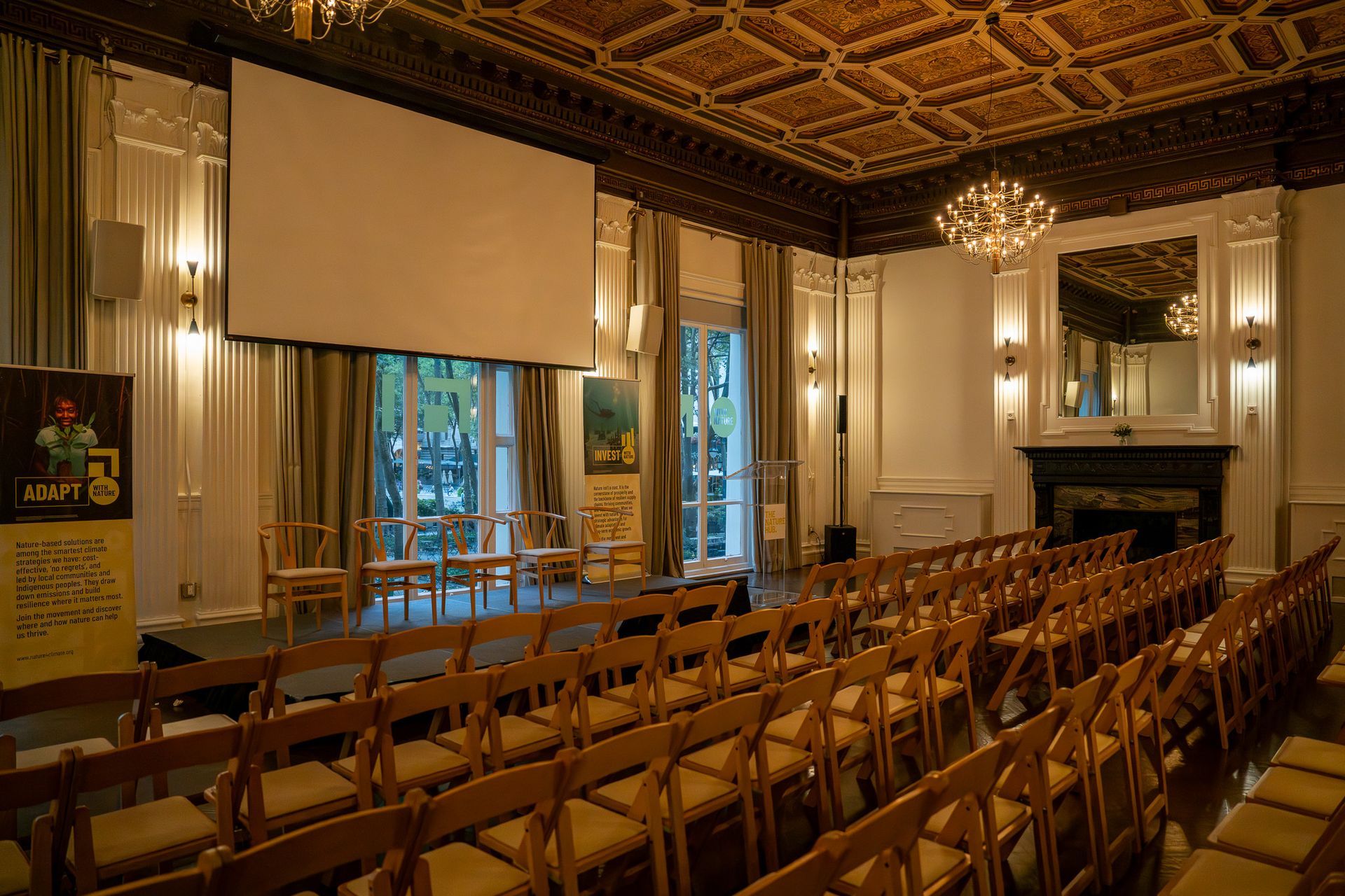 Empty conference room with rows of chairs, a projection screen, and chandeliers in a warmly lit historic interior