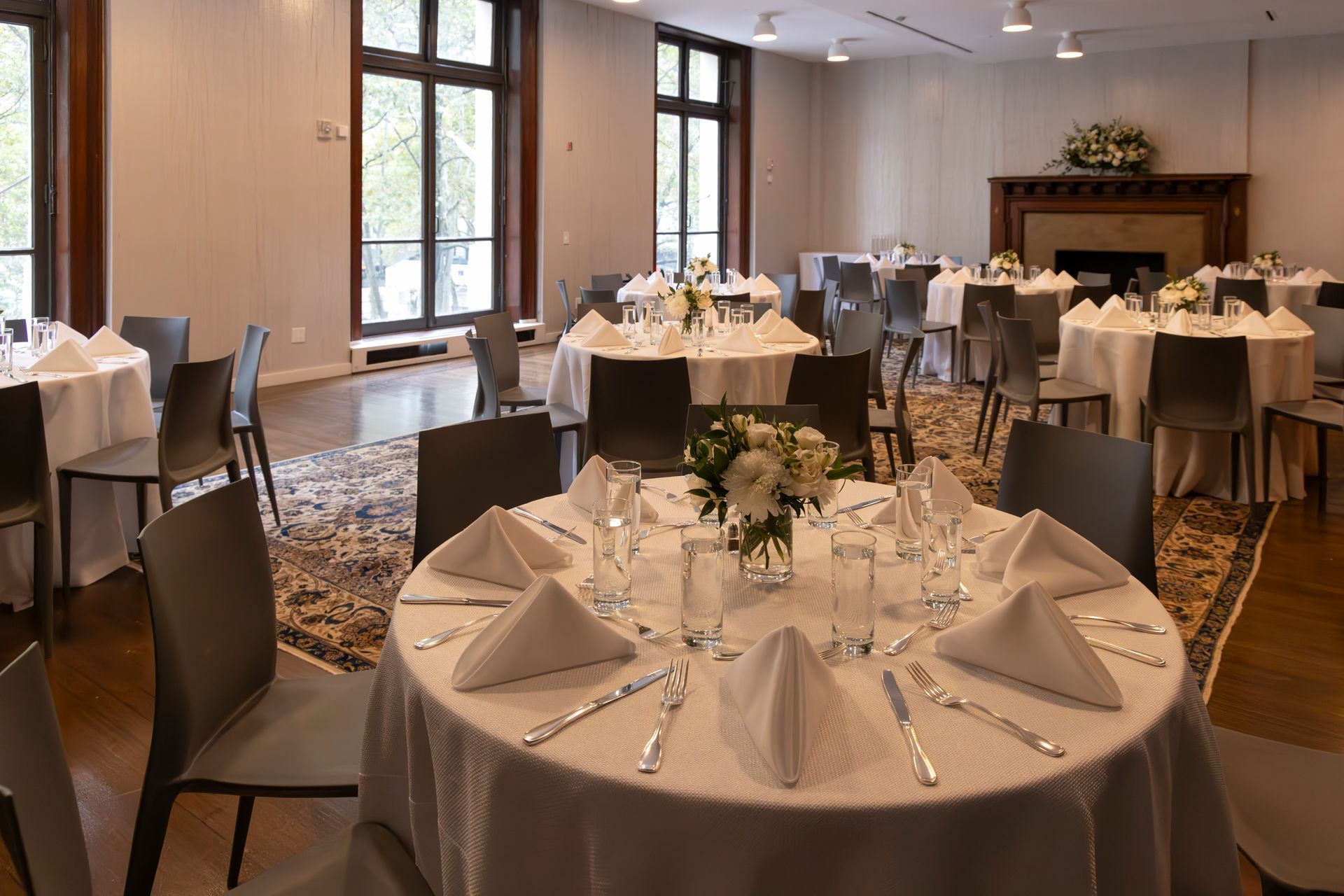 Elegant banquet hall with round tables set for a formal event and fireplace in the background