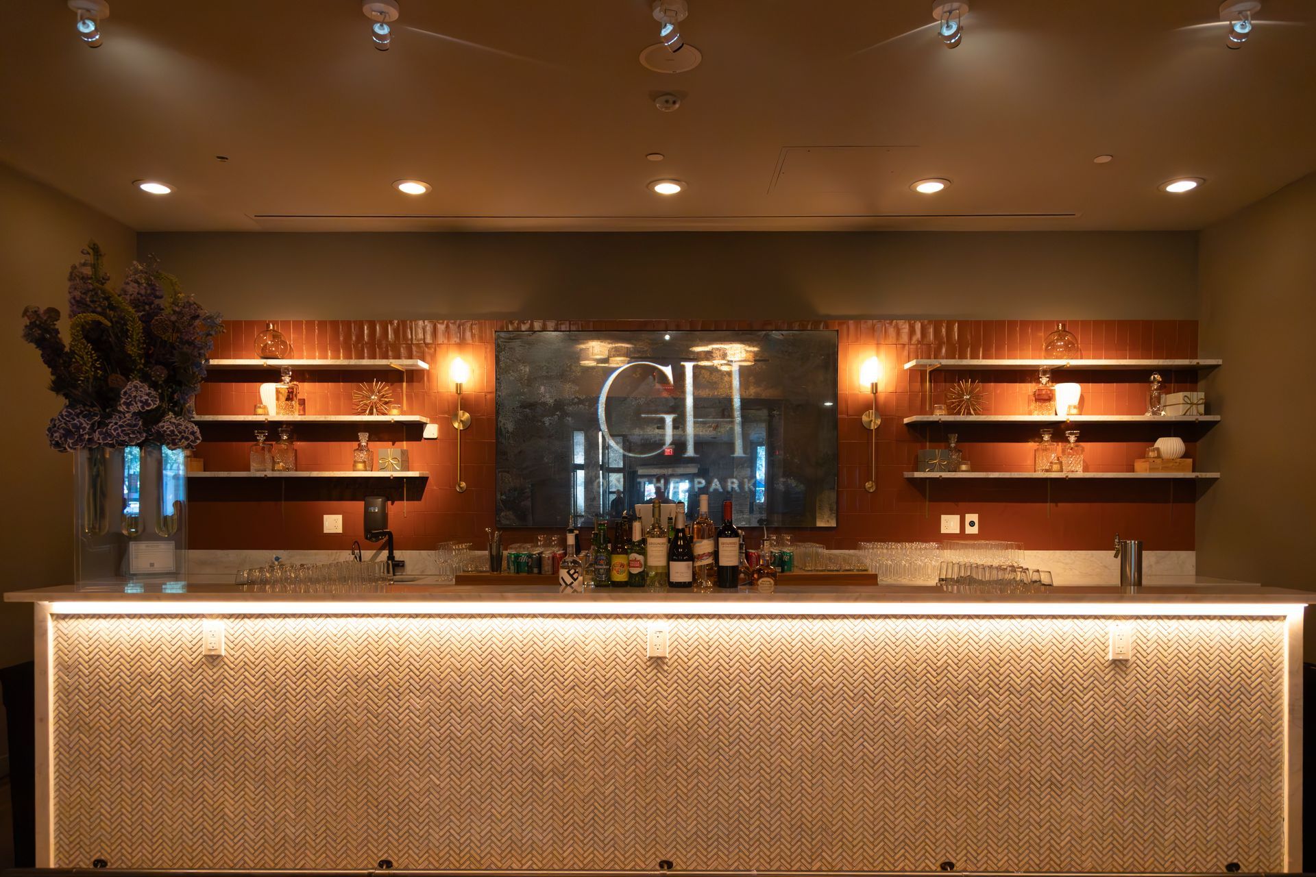 Modern bar interior with backlit shelves, bottles, and a glowing patterned front counter