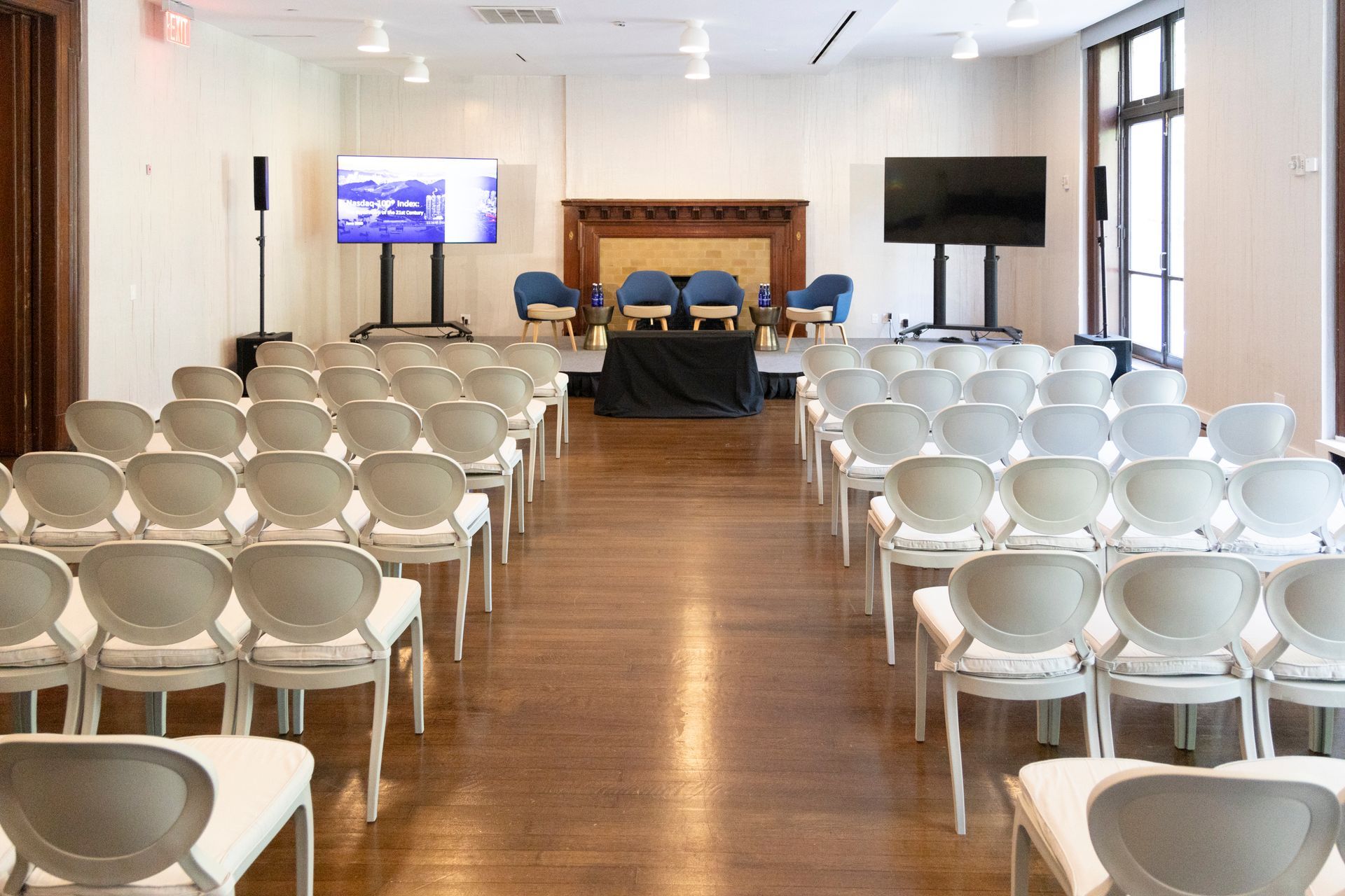 White chairs arranged in rows in a bright conference room with a screen and stage area at the front