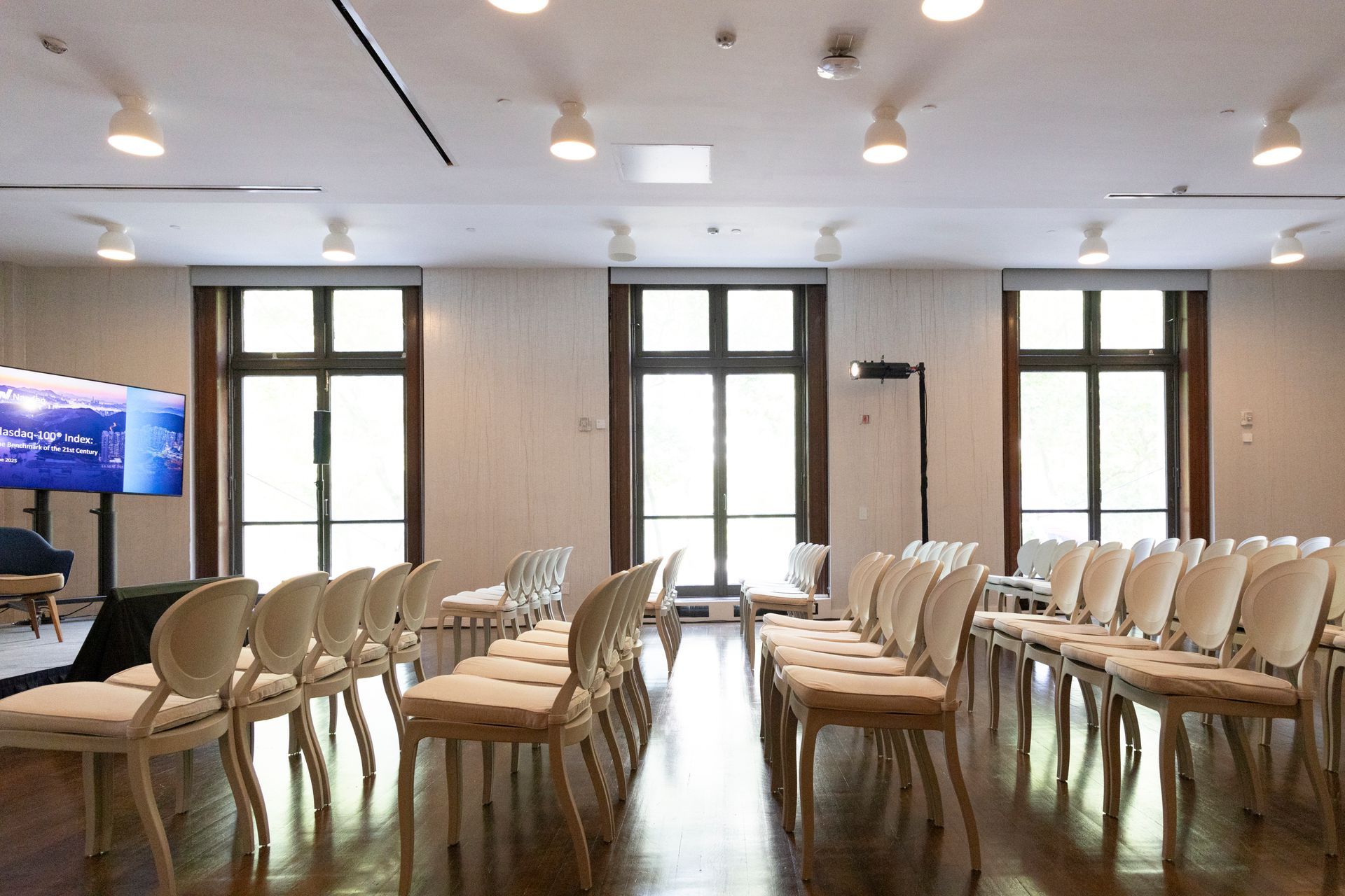 Empty conference room with rows of beige chairs, large windows, and bright overhead lights