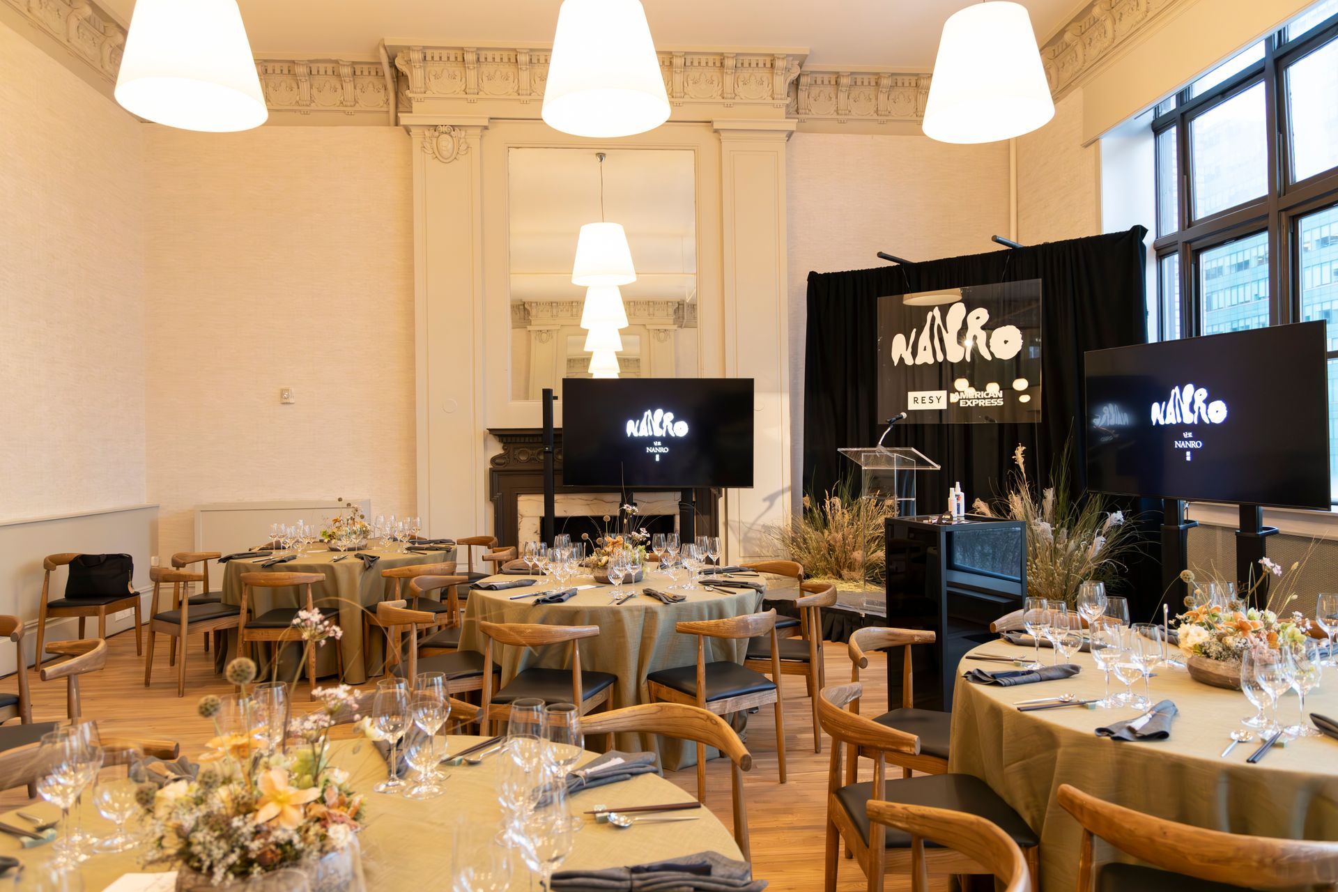 Elegant banquet hall with round tables set for a formal event, chandeliers overhead, and large screens at the front