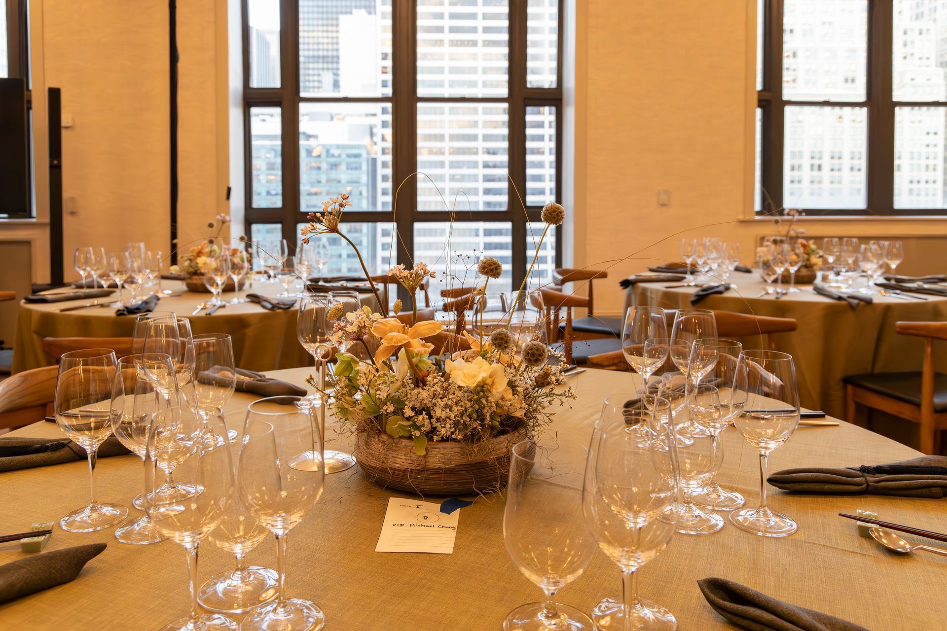 Elegant dining table set for a formal event in a bright room with large windows and city views