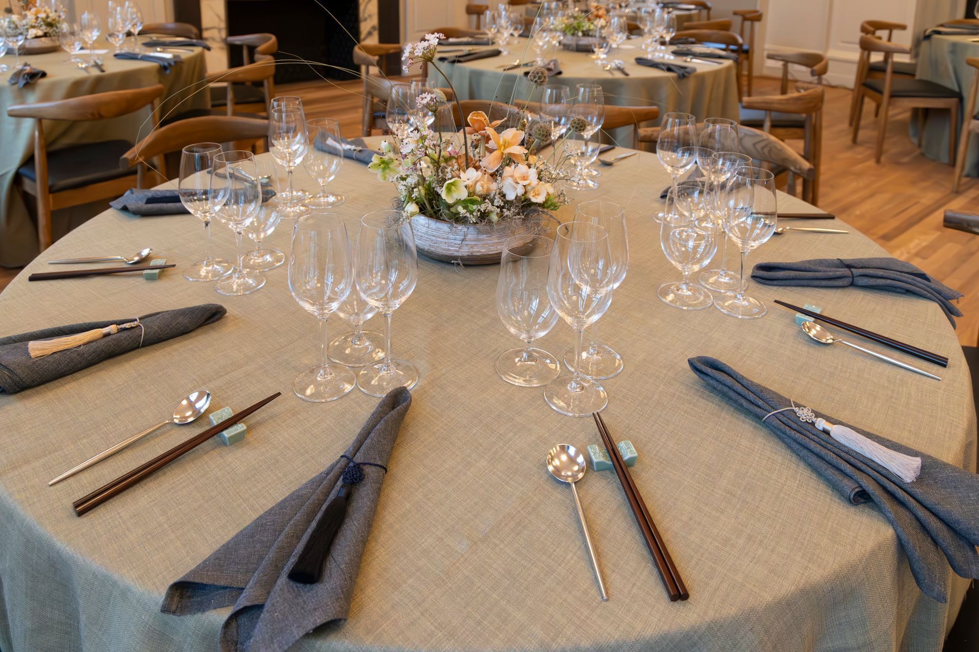 Round banquet table set with blue napkins, glassware, and a floral centerpiece in a dining room