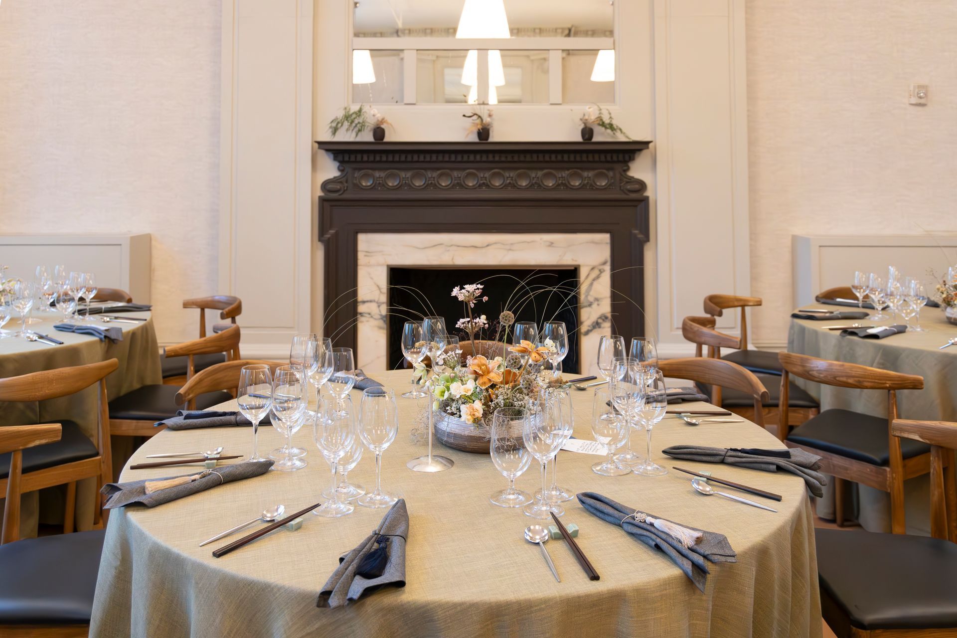 Elegant dining room with a set round table in front of a fireplace and mirrors