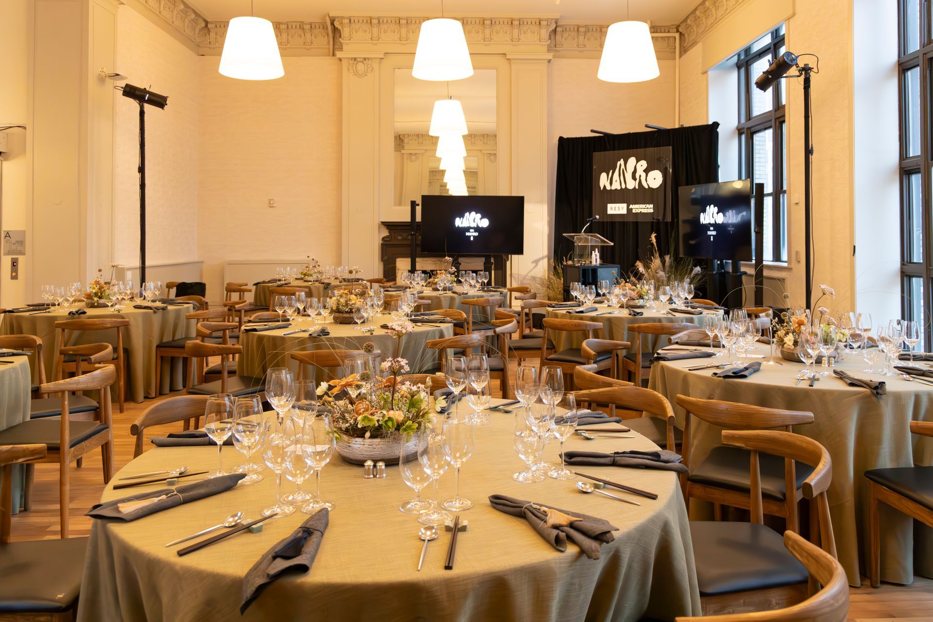 Elegant restaurant dining room set with round tables, chairs, white tablecloths, and warm hanging lights