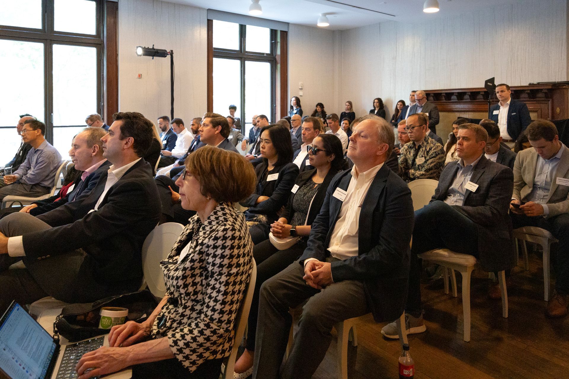 Audience seated in a bright meeting room, listening to a presentation