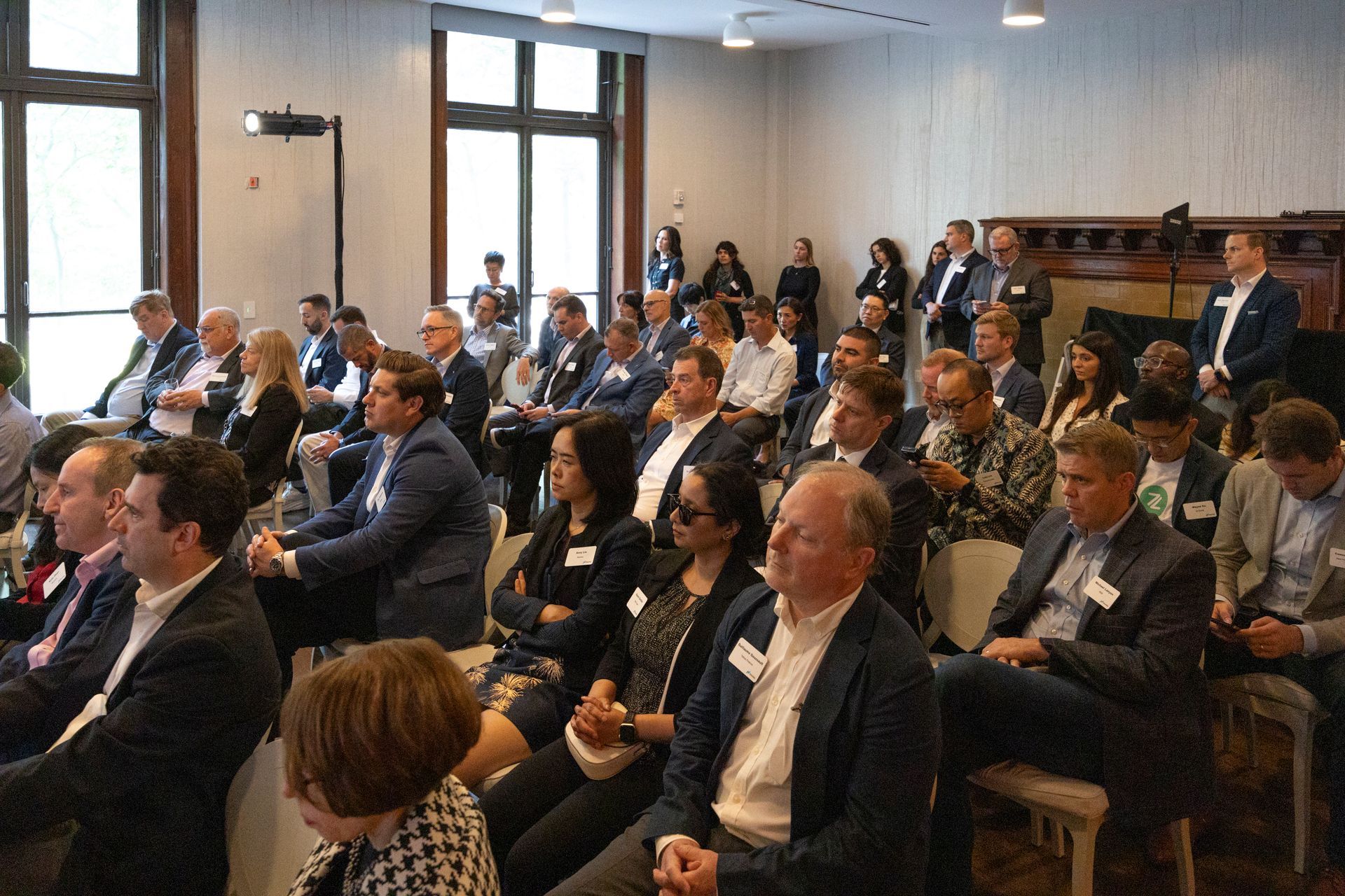 Audience seated in a conference room, listening attentively during a presentation