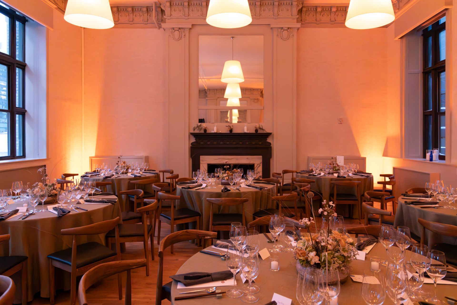 Elegant dining room with set tables, warm lighting, and a fireplace at the far end