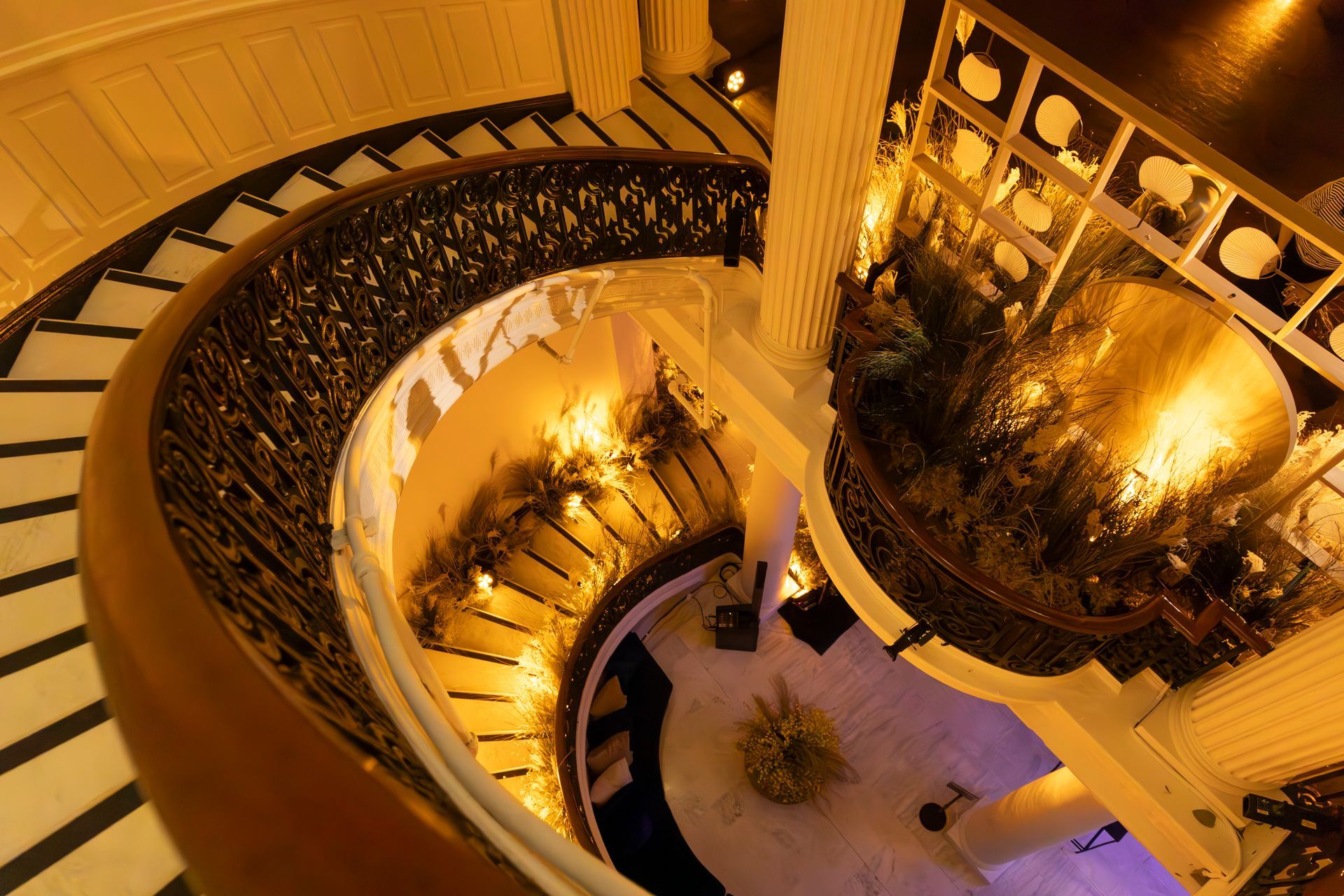 Curved staircase with black railing and warm golden lighting viewed from above