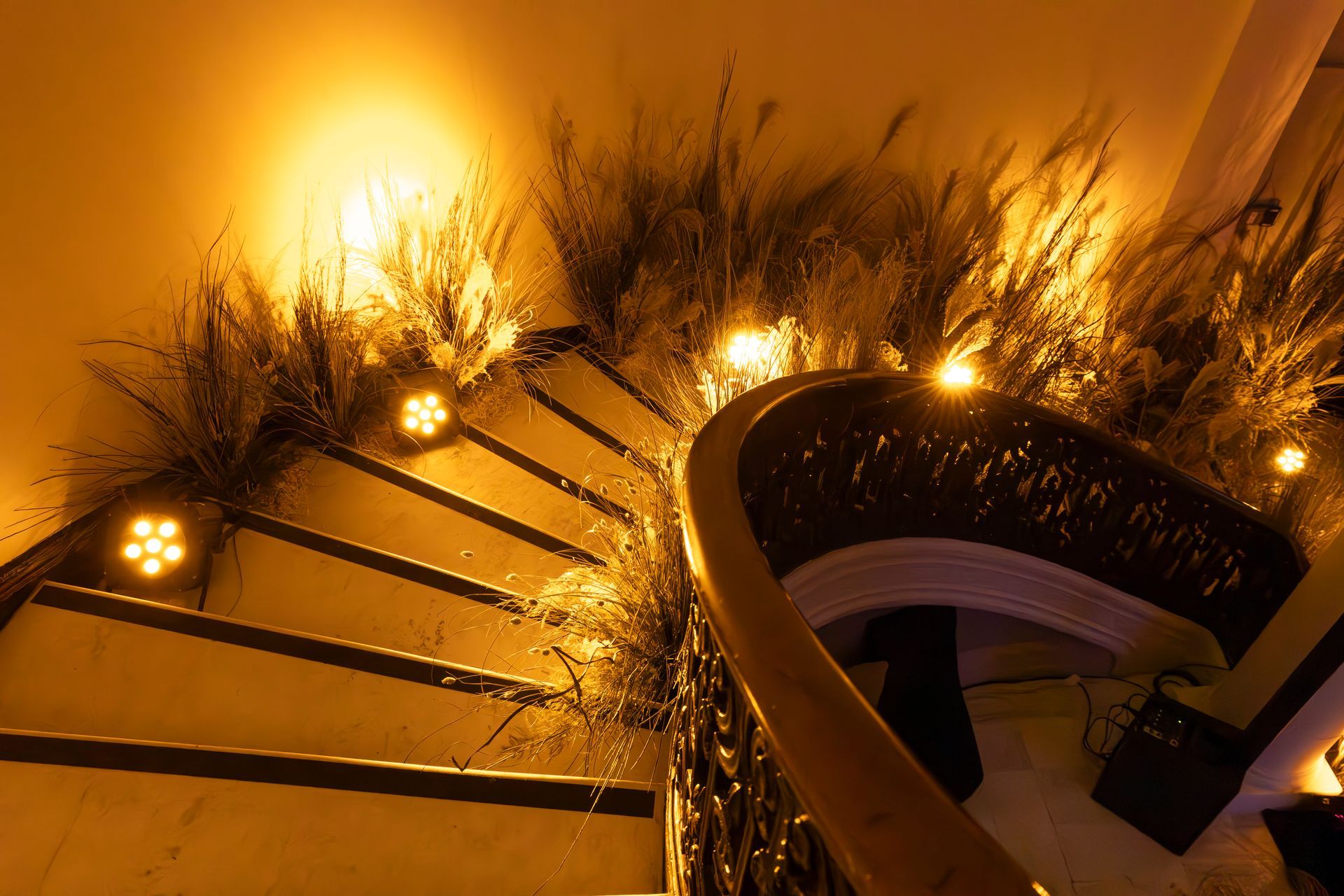 Golden-lit spiral staircase with glowing lights and dark railing at night