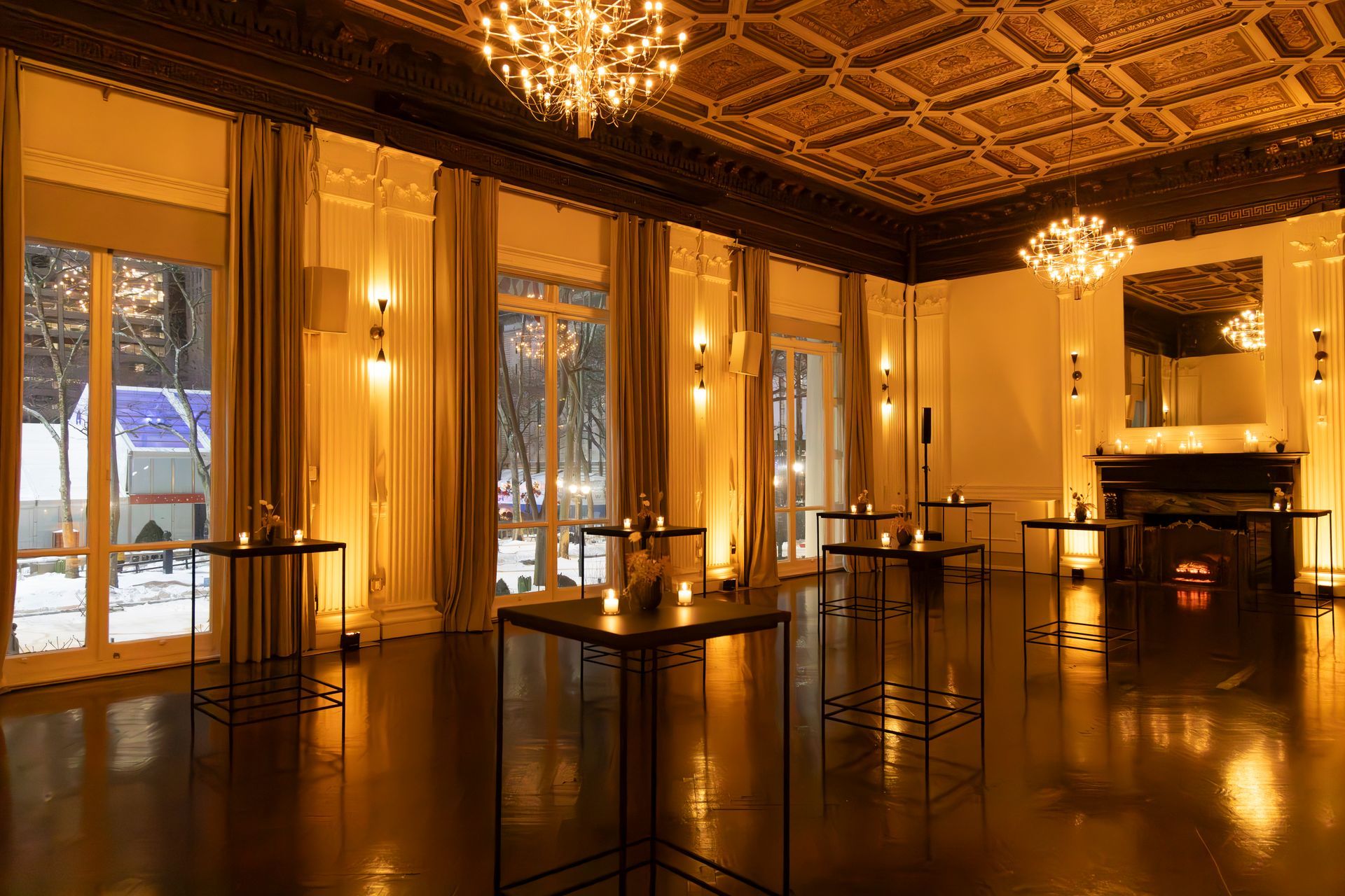Elegant, warmly lit ballroom with chandeliers, mirrored walls, and tables on a polished floor