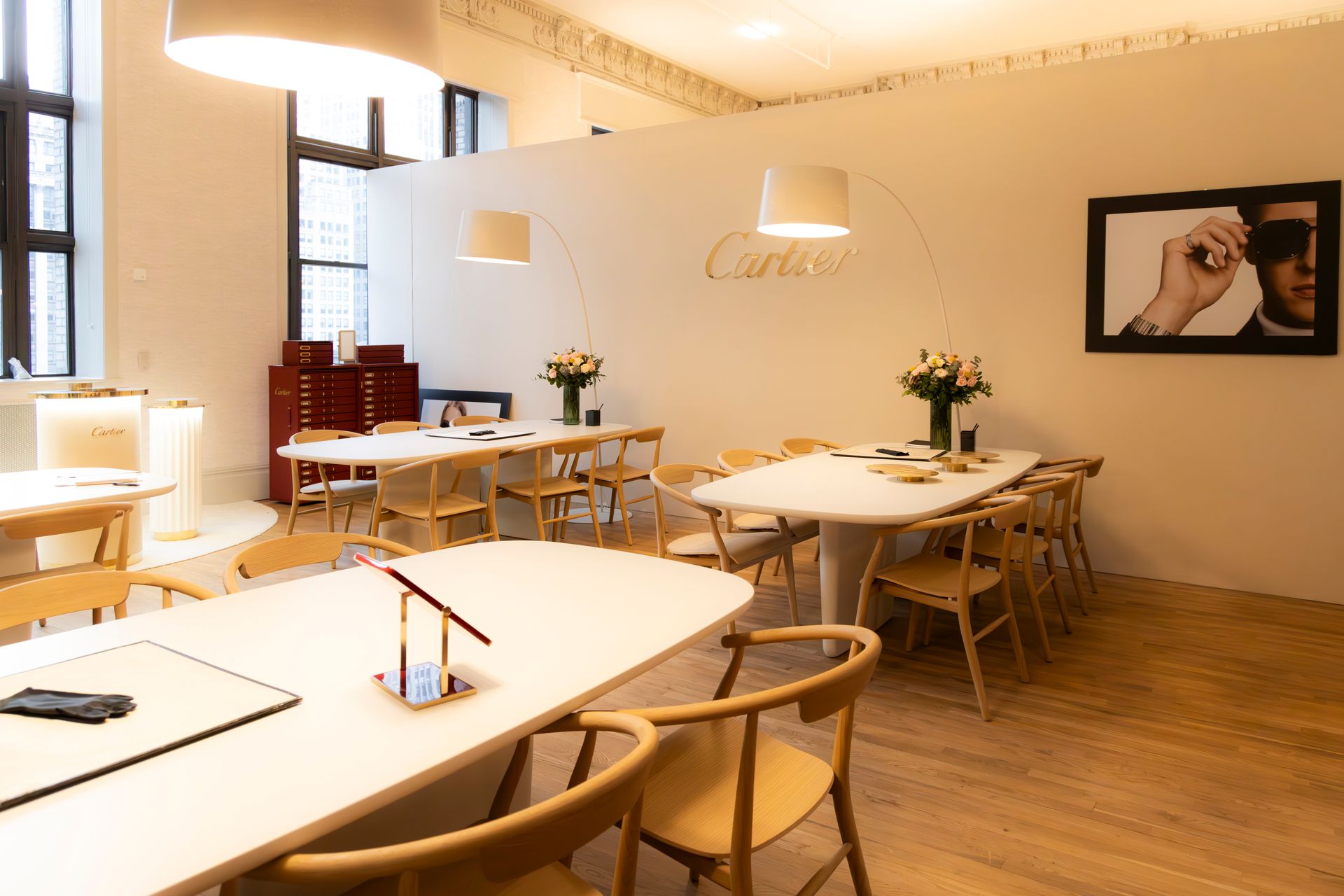 Bright, modern café interior with wooden tables, chairs, and soft wall art on cream-colored walls.