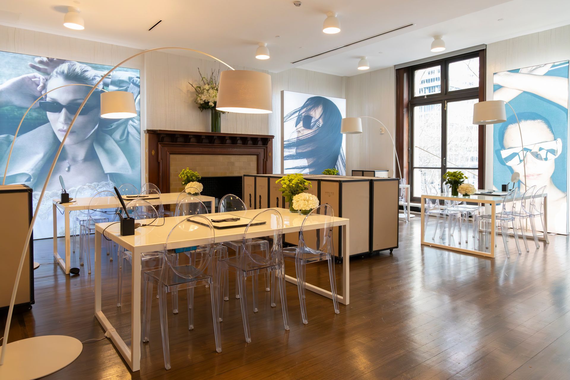 Bright modern dining room with long wooden tables, clear chairs, and large blue-and-white mural panels