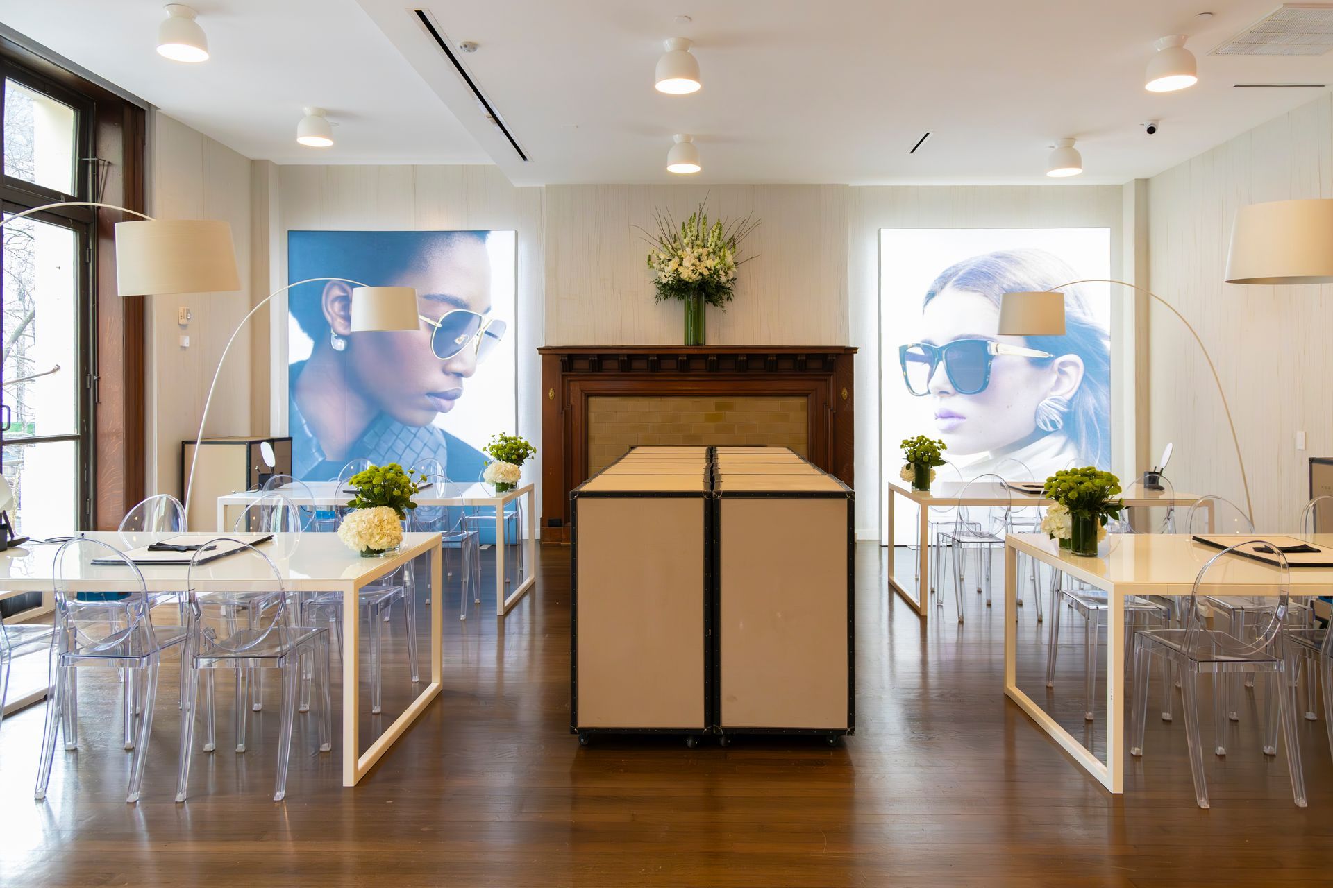 Modern wedding ceremony setup with white chairs, floral arrangements, and portraits flanking a fireplace.
