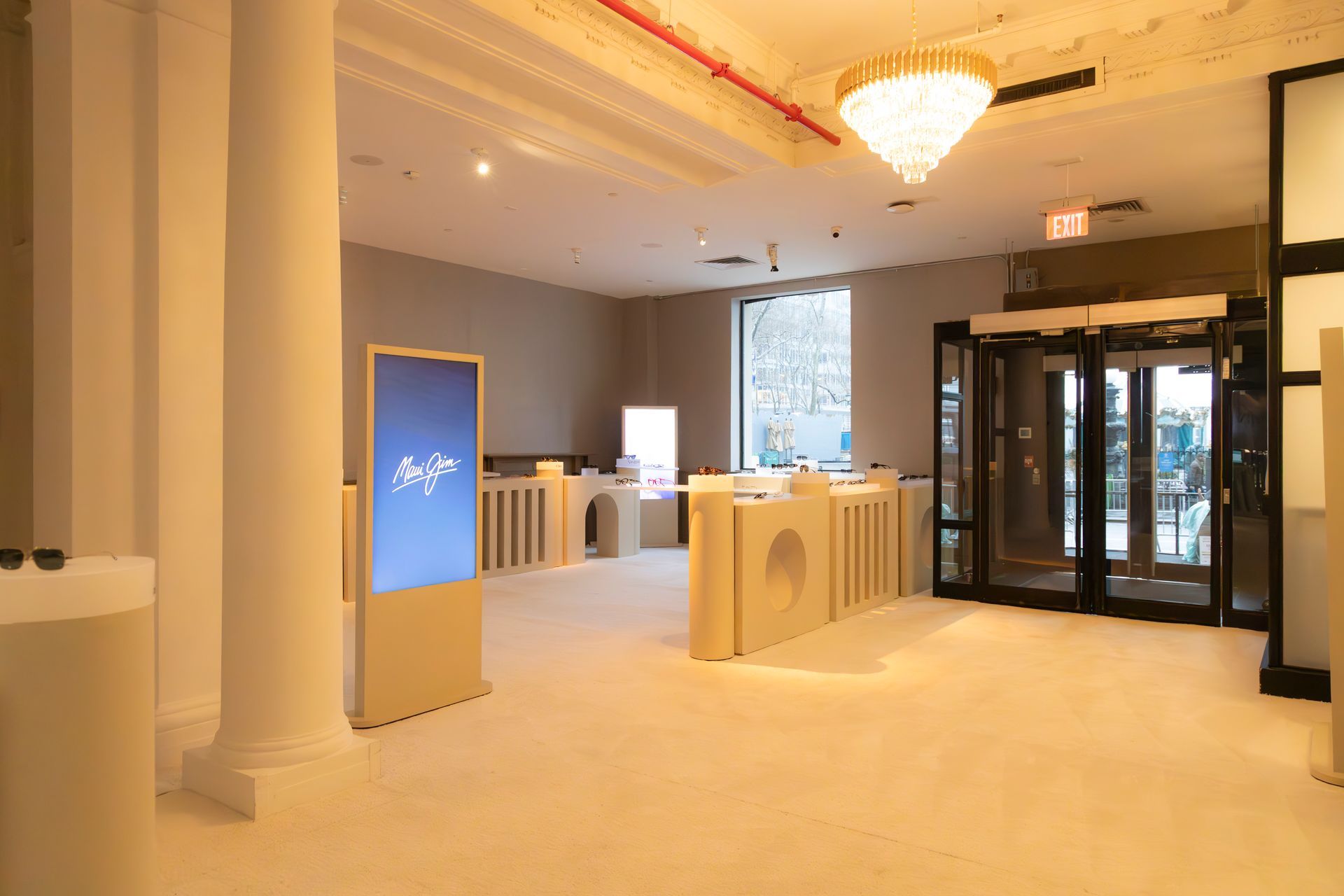 Bright hotel lobby with chandeliers, cream decor, and glass revolving door入口