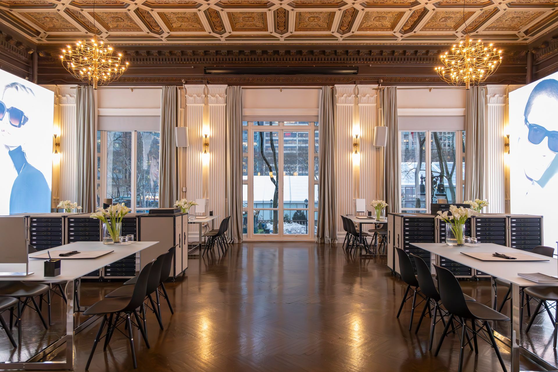 Elegant dining room with mirrored walls, ornate ceiling, and tables set by large windows