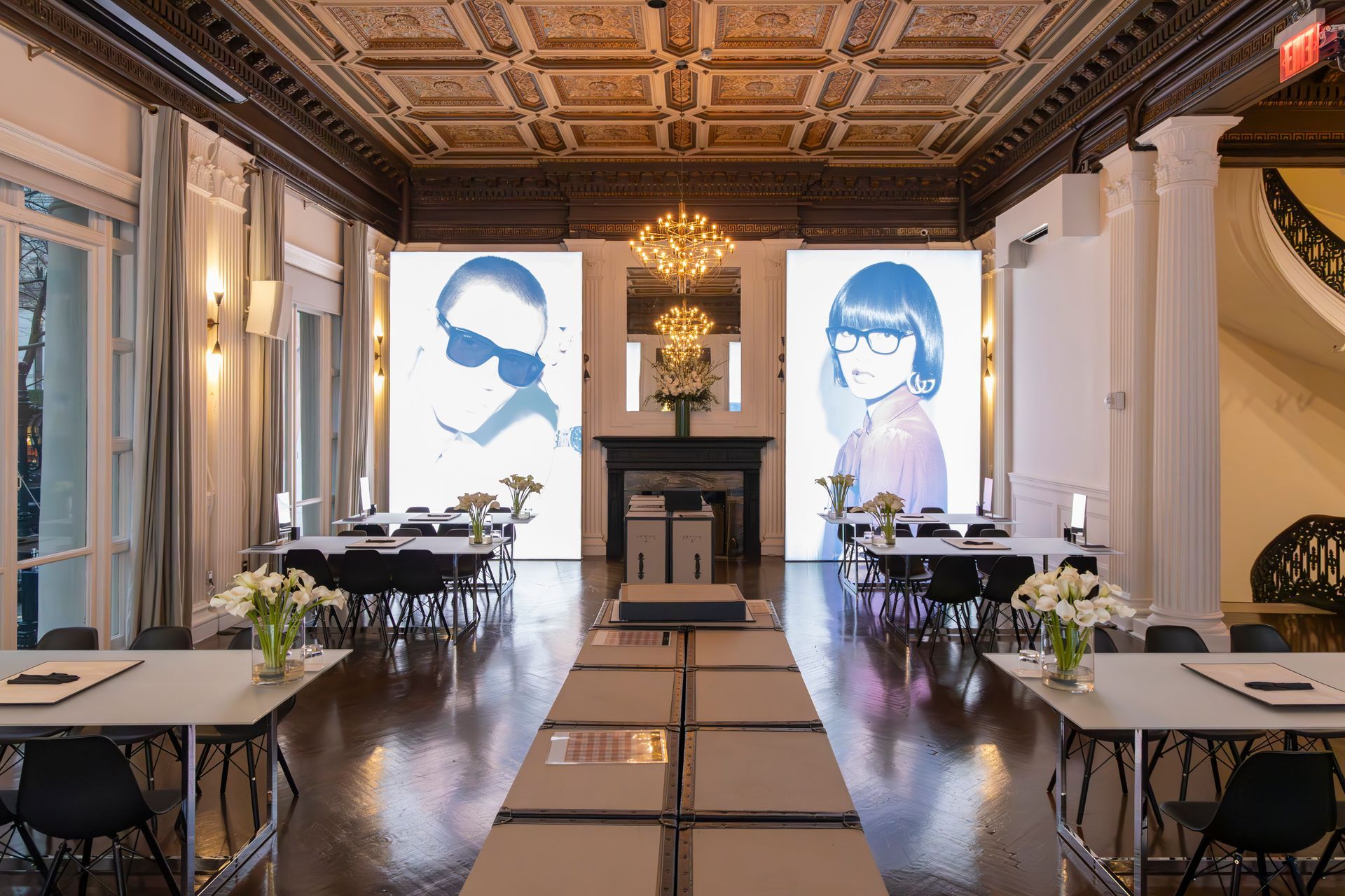 Elegant dining room with long tables, a chandelier, and two large portrait panels at the far end.