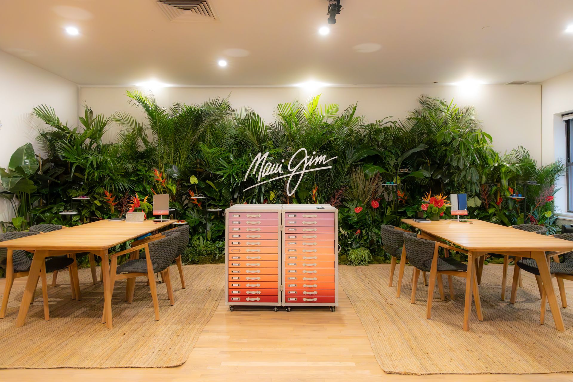 Indoor plant shop with lush green wall, wooden tables, and a colorful menu display in the center.