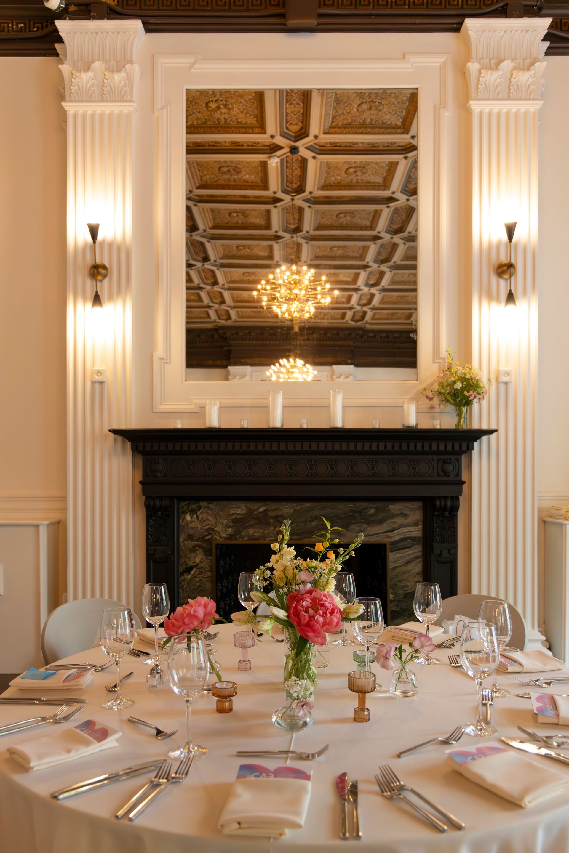 Elegant dining room with a set table, chandelier, ornate ceiling, and fireplace centerpiece
