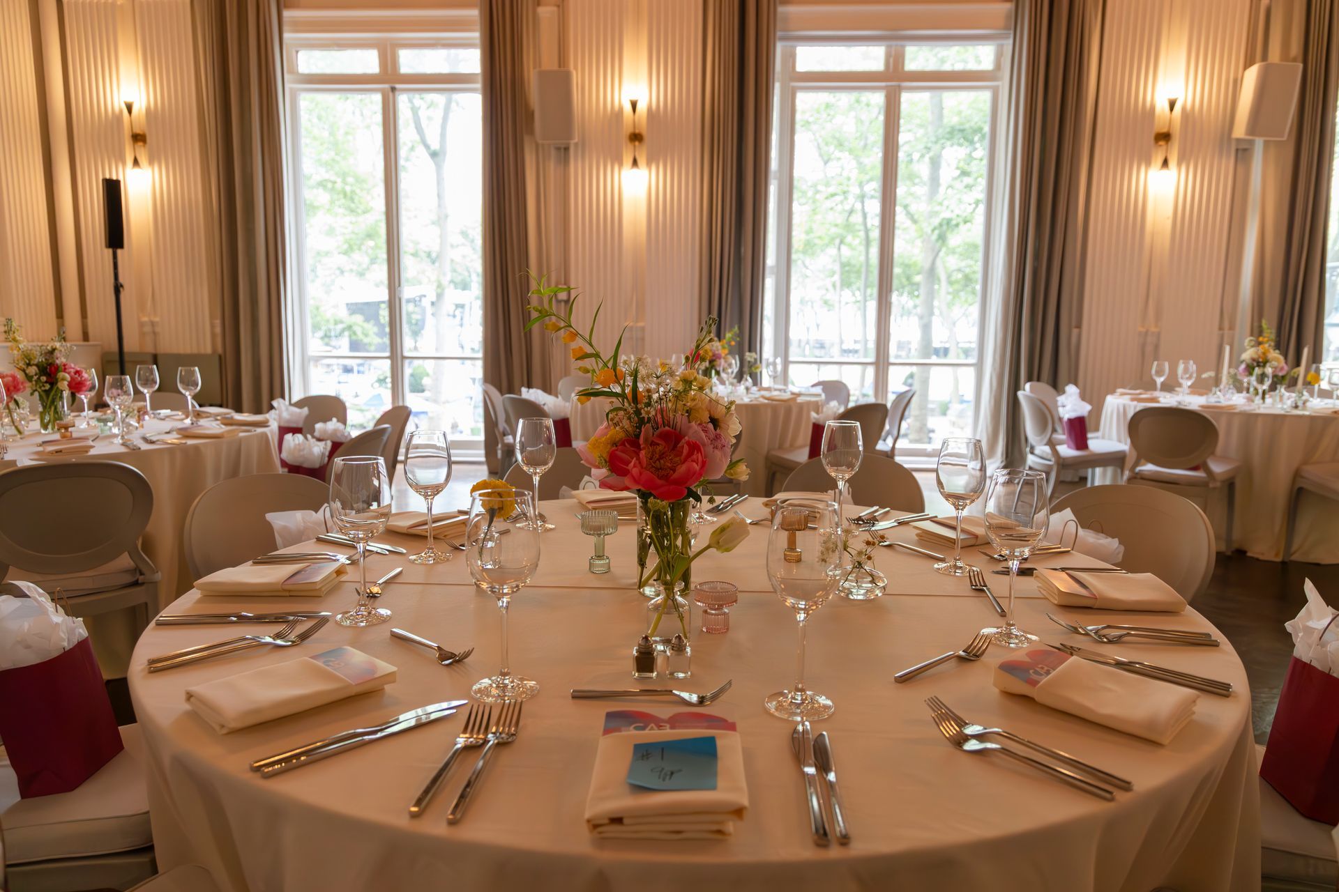 Elegantly set banquet table in a bright dining room with large windows and floral centerpiece