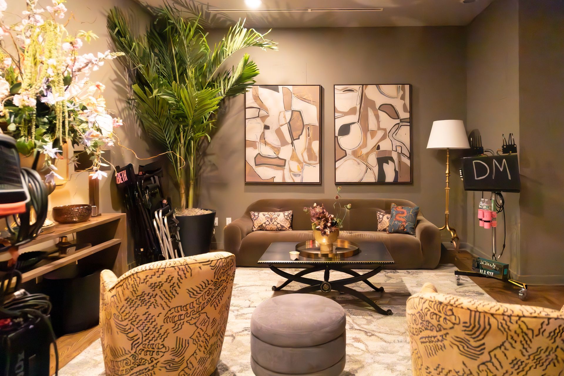Cozy living room with floral chairs, sofa, coffee table, lamp, and large plants in warm neutral tones
