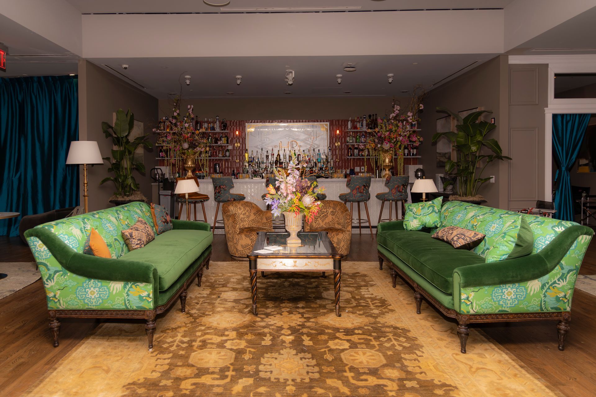 Living room with green sofas, coffee table, and floral arrangements in a warmly lit sitting area