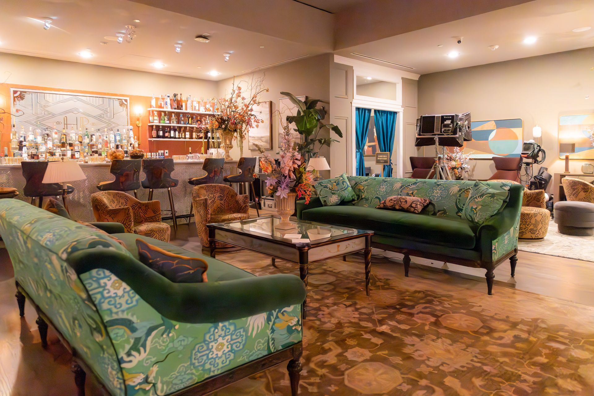 Elegant living room with green sofas, patterned rug, and warm lighting, resembling a stylish lounge.