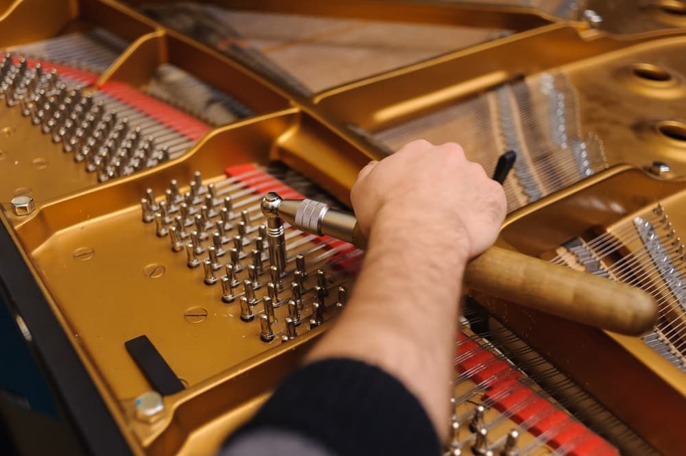 A Person Is Working on A Piano with A Screwdriver — Tony Prince Piano Tuning In Kempsey, NSW