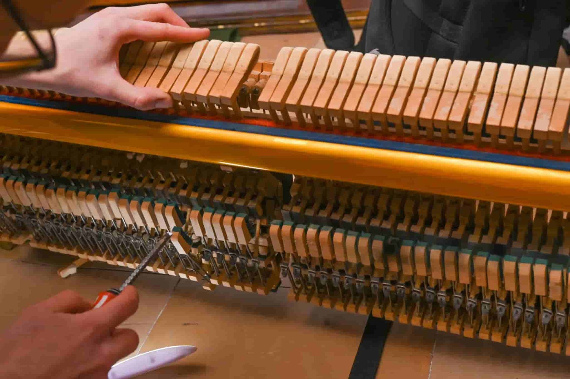 A Person Is Working on A Piano with A Screwdriver — Tony Prince Piano Tuning In Port Macquarie, NSW