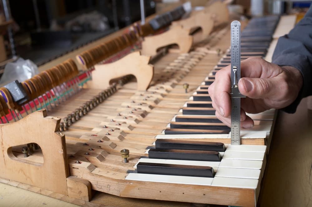 A Person Is Measuring a Piano Keyboard with A Ruler — Tony Prince Piano Tuning In Taree, NSW