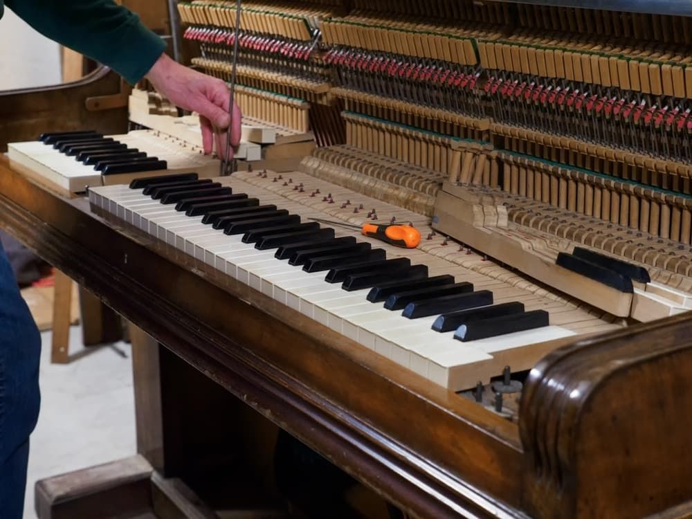 A Person Is Working on A Piano Keyboard with A Brush — Tony Prince Piano Tuning In Coffs Harbour, NSW