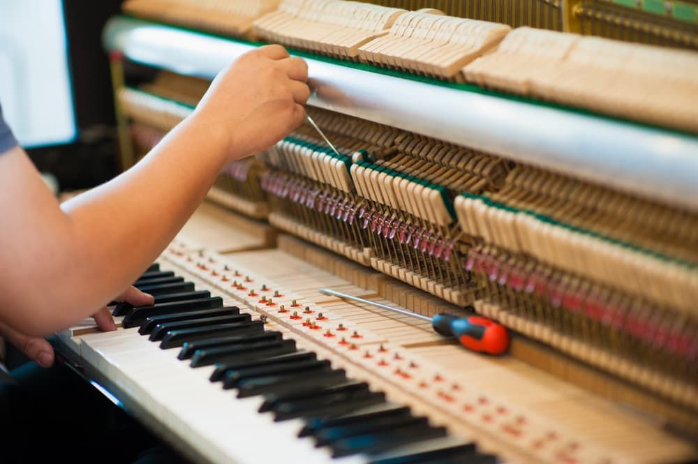 A Person is Working on a Piano Using a Tool — Tony Prince Piano Tuning In Taree, NSW