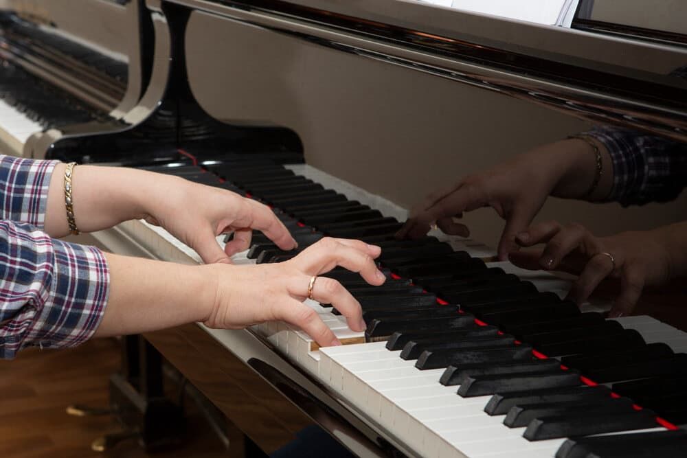 A Person Is Playing a Piano with Their Hands on The Keys — Tony Prince Piano Tuning In Taree, NSW