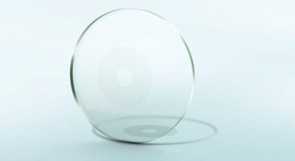 Clear, circular lens with a pattern of small dots, casting a shadow.