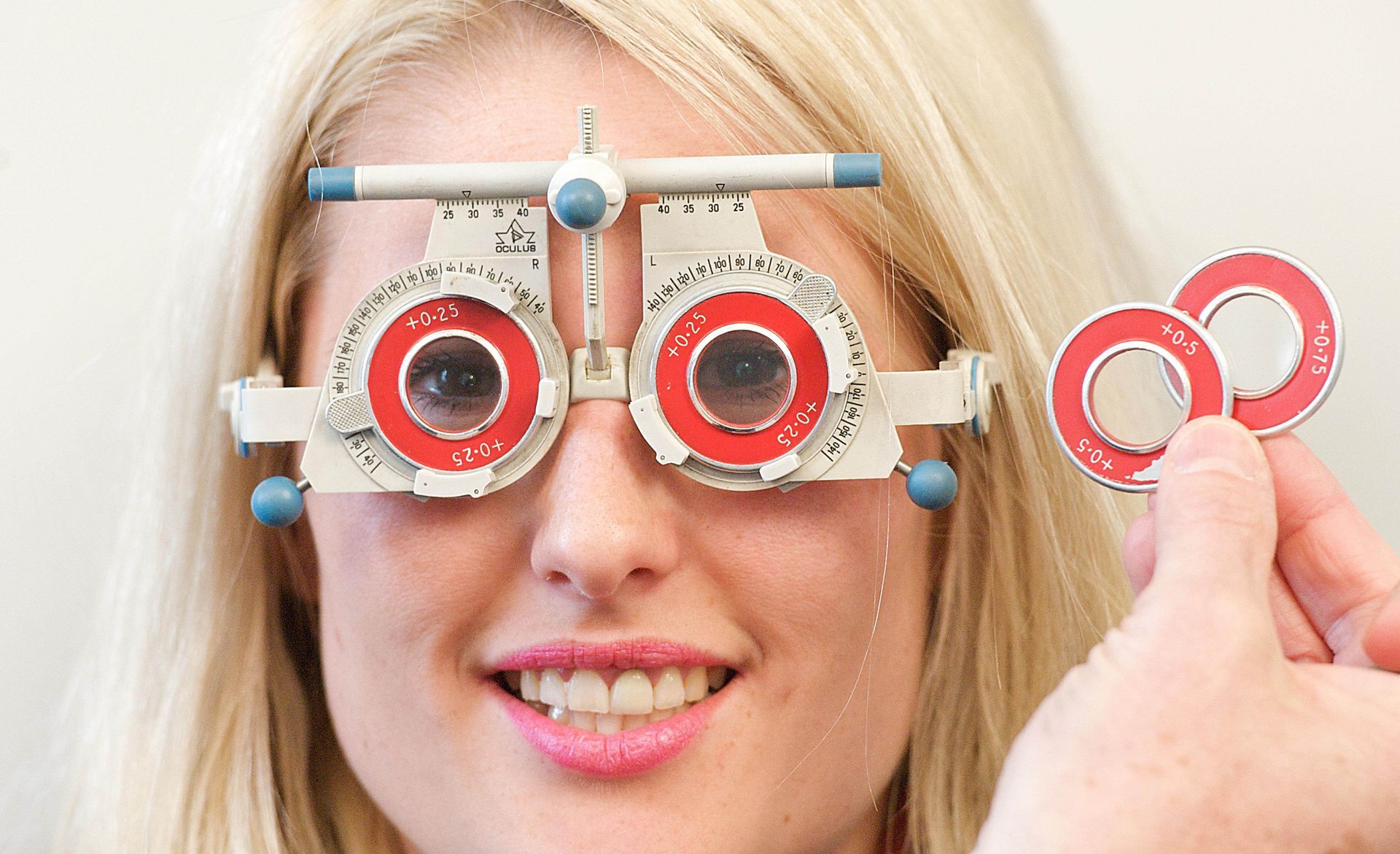 Woman getting an eye exam with an ophthalmic test frame and lenses.
